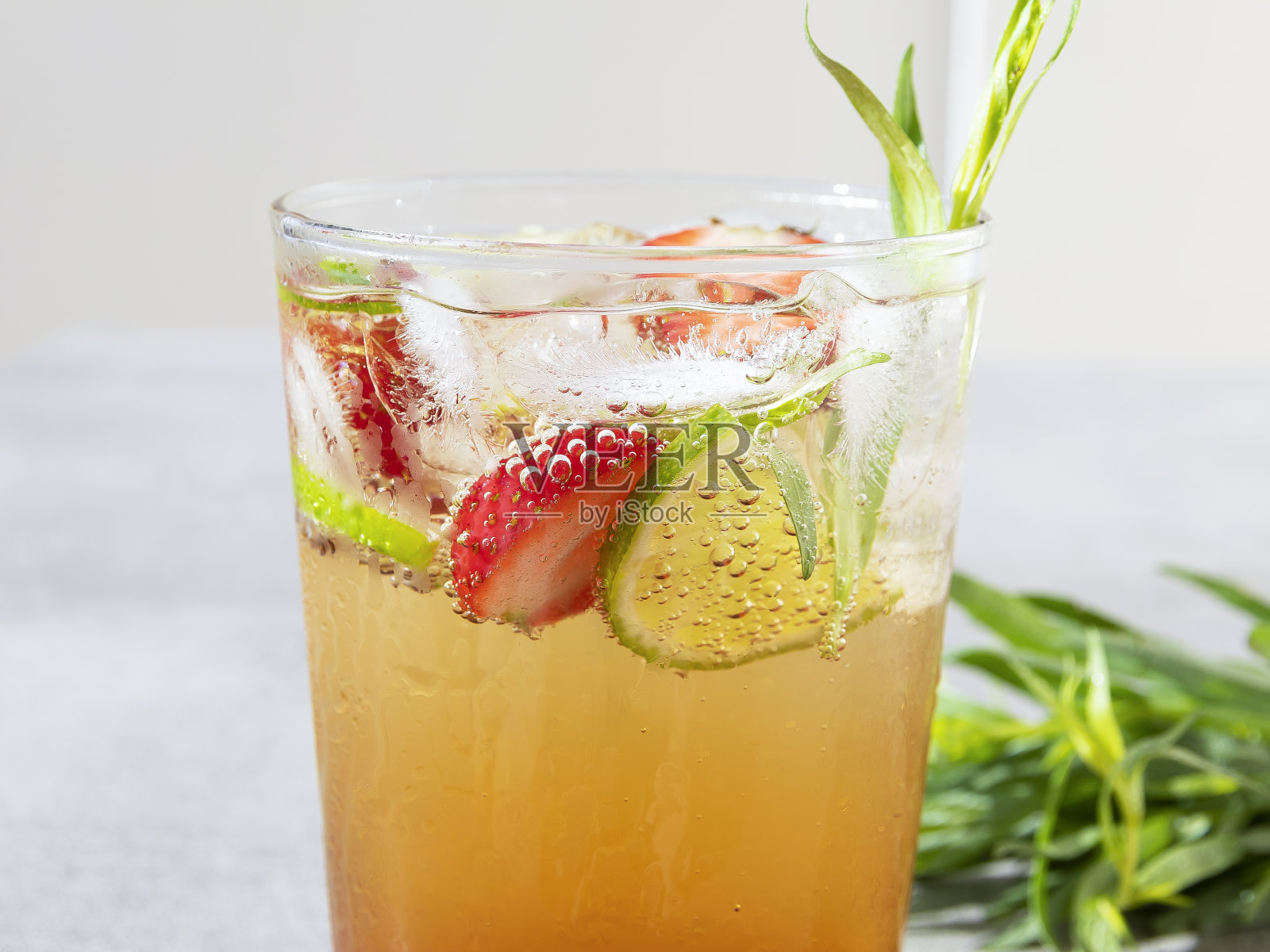 清爽的夏日鸡尾酒饮柠檬水与冰，青柠，草莓龙蒿杯近距离接触照片摄影图片