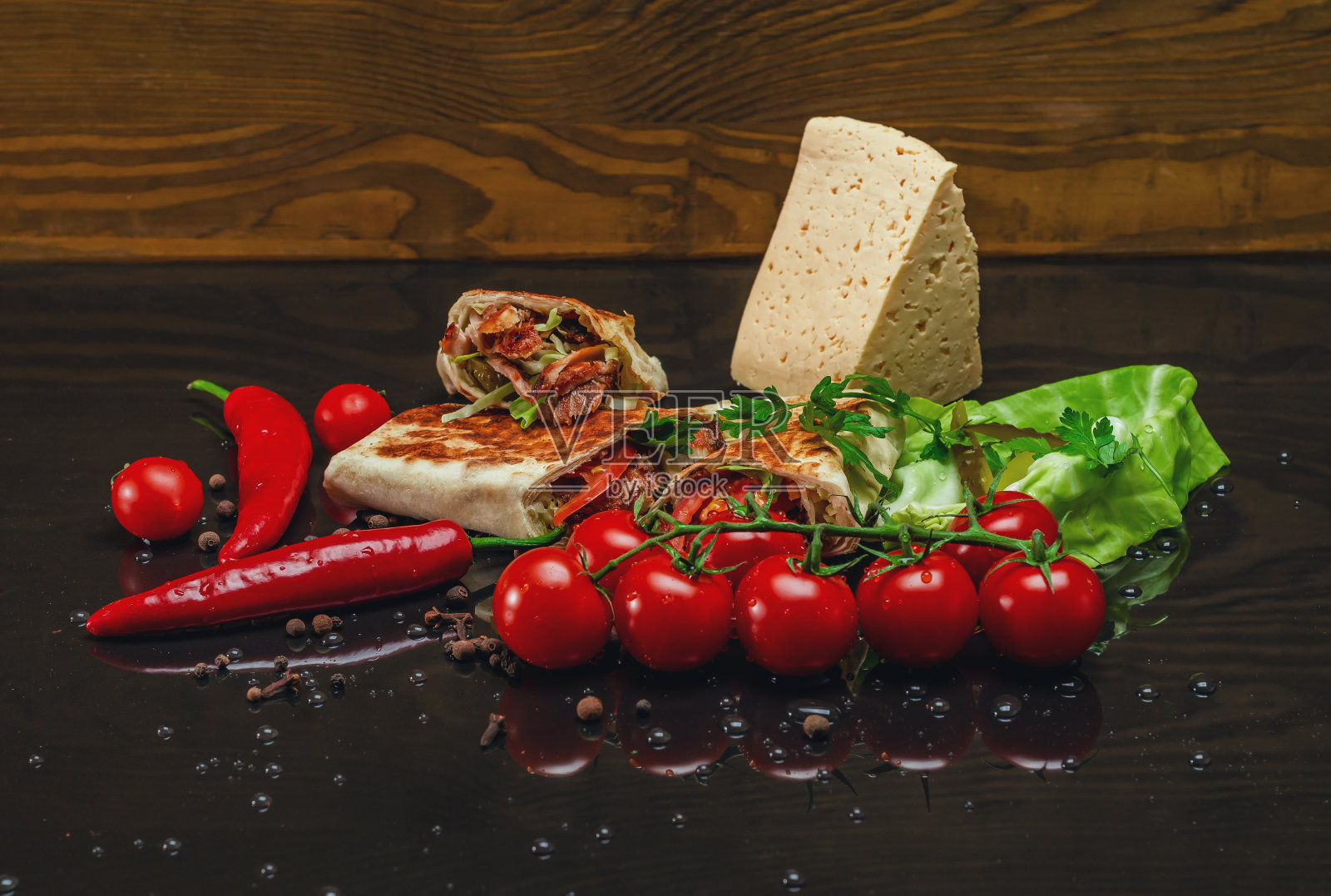 烤肉、红辣椒、樱桃番茄、卷心菜和奶酪在黑色木质背景上的构图照片摄影图片