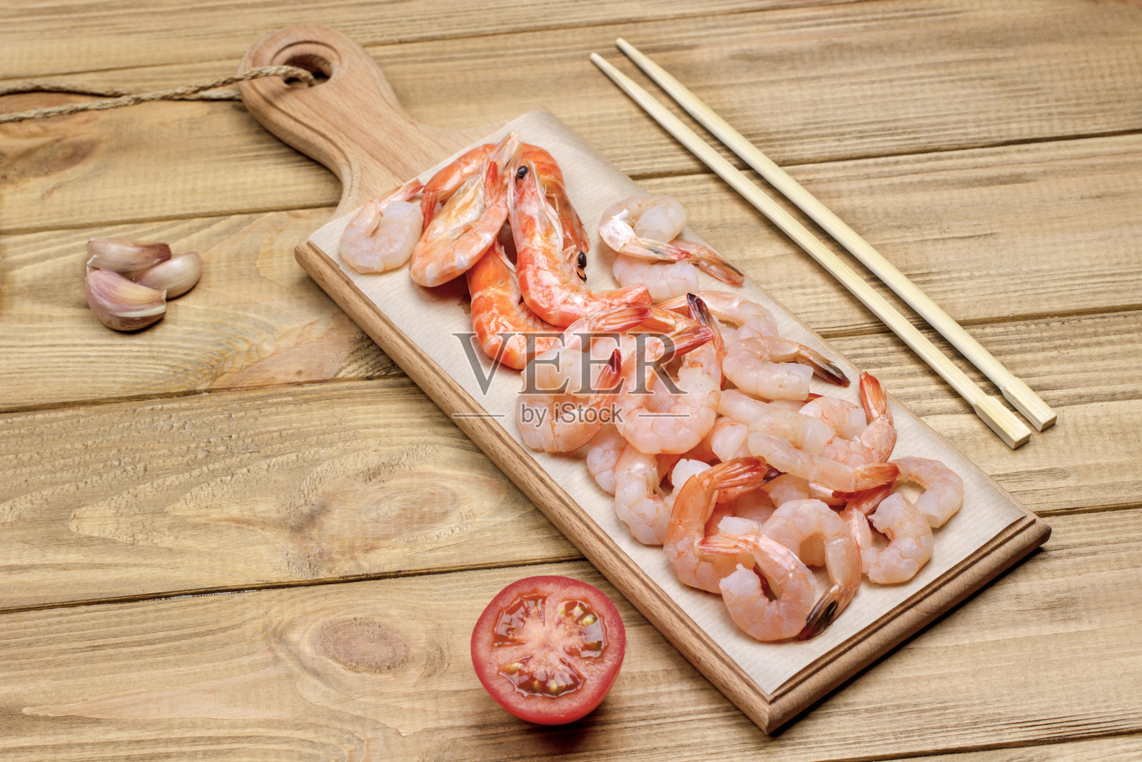虾放在砧板上。一半西红柿，蒜瓣和竹竿照片摄影图片