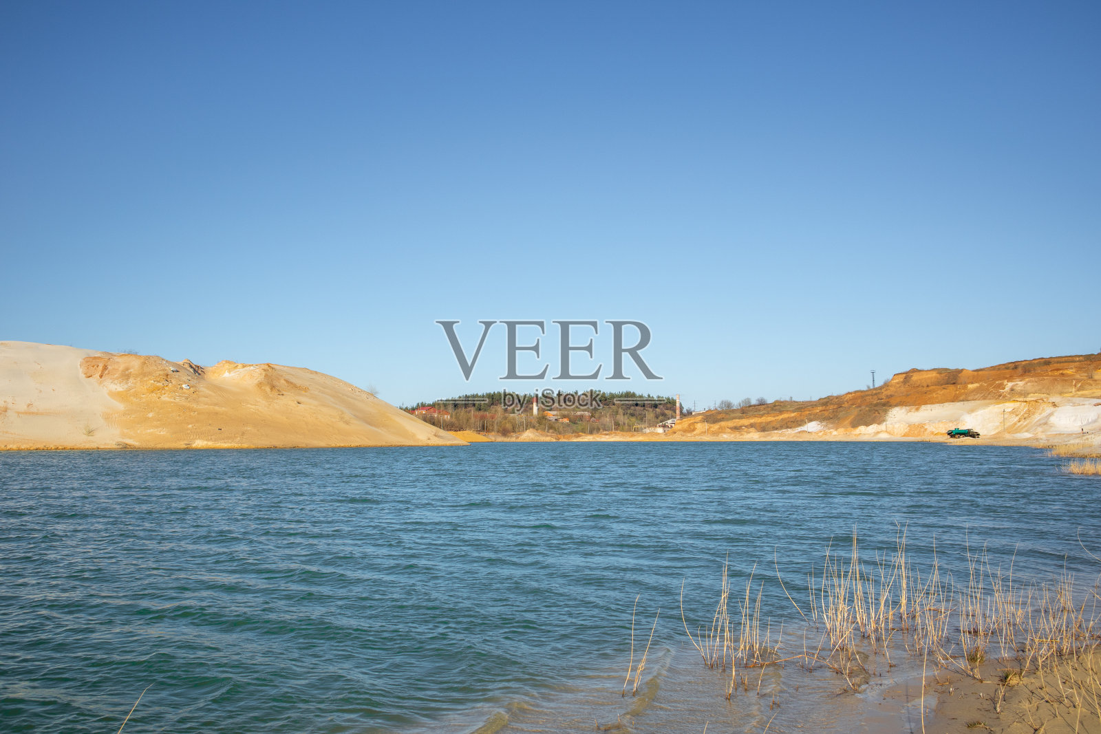 蓝色的海水和沙滩上的小波浪。采石场上的池塘。照片摄影图片