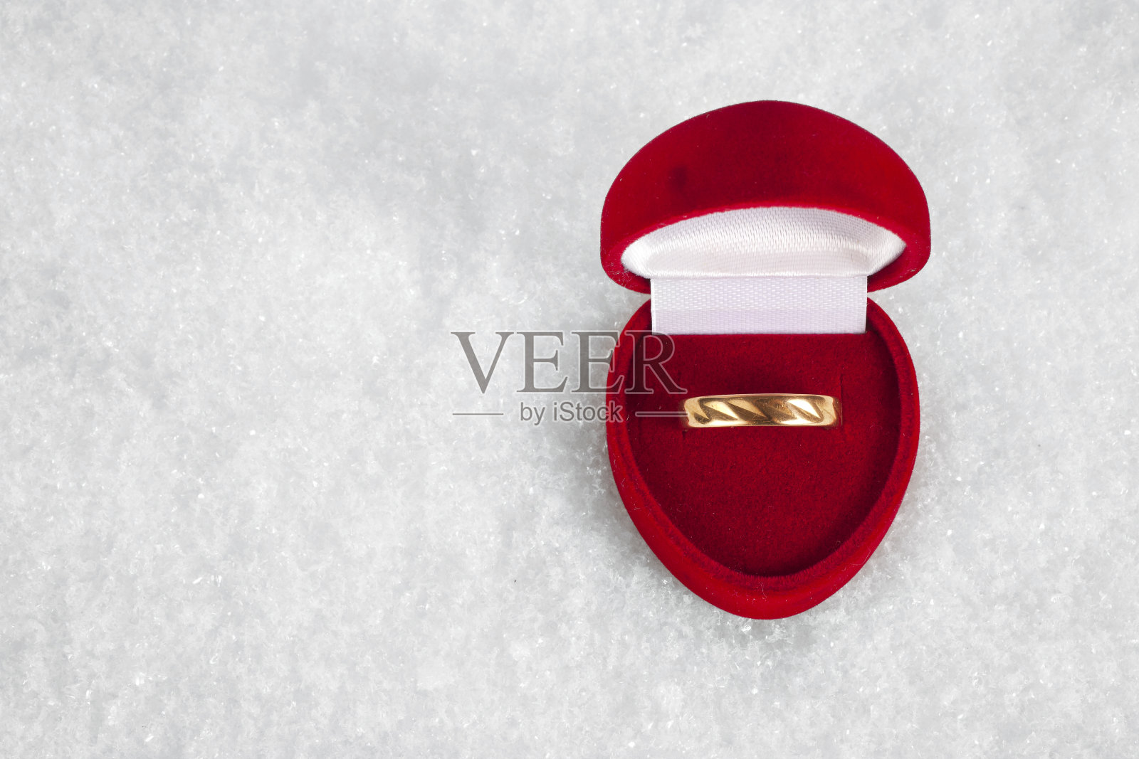 结婚戒指放在雪地上的盒子里。照片摄影图片