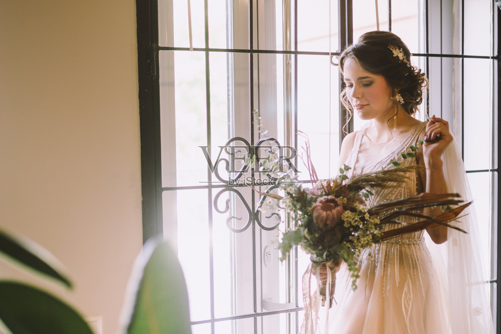 优雅的早晨的照片。的婚礼。新娘。准备。新娘拿着一束花靠近窗户。欧式婚礼。早晨新娘在婚礼当天等待新郎照片摄影图片