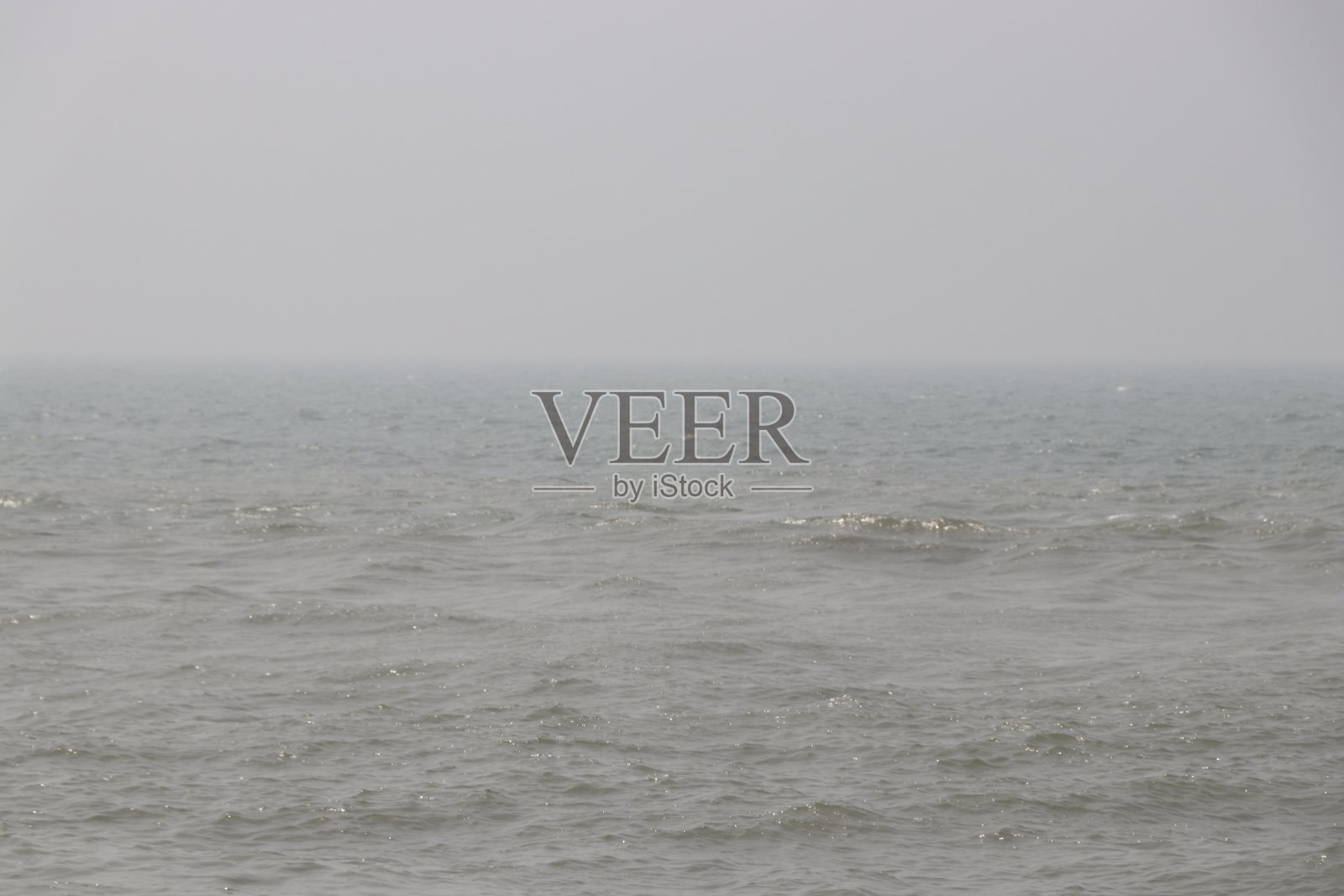 大海的表面，清澈的蓝天下没有波浪的河流。有阳光的水面照片摄影图片