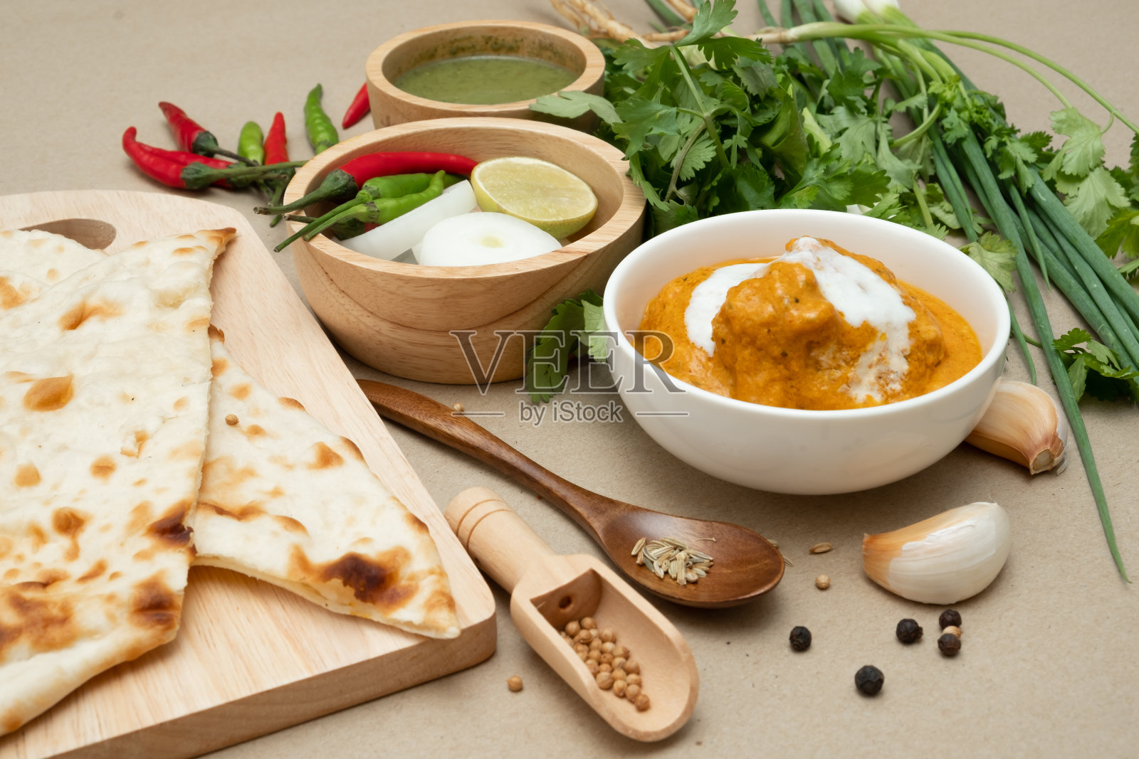 印度食物黄油鸡和馕在干净的棕色背景。以蒜、胡椒等香料作装饰。照片摄影图片