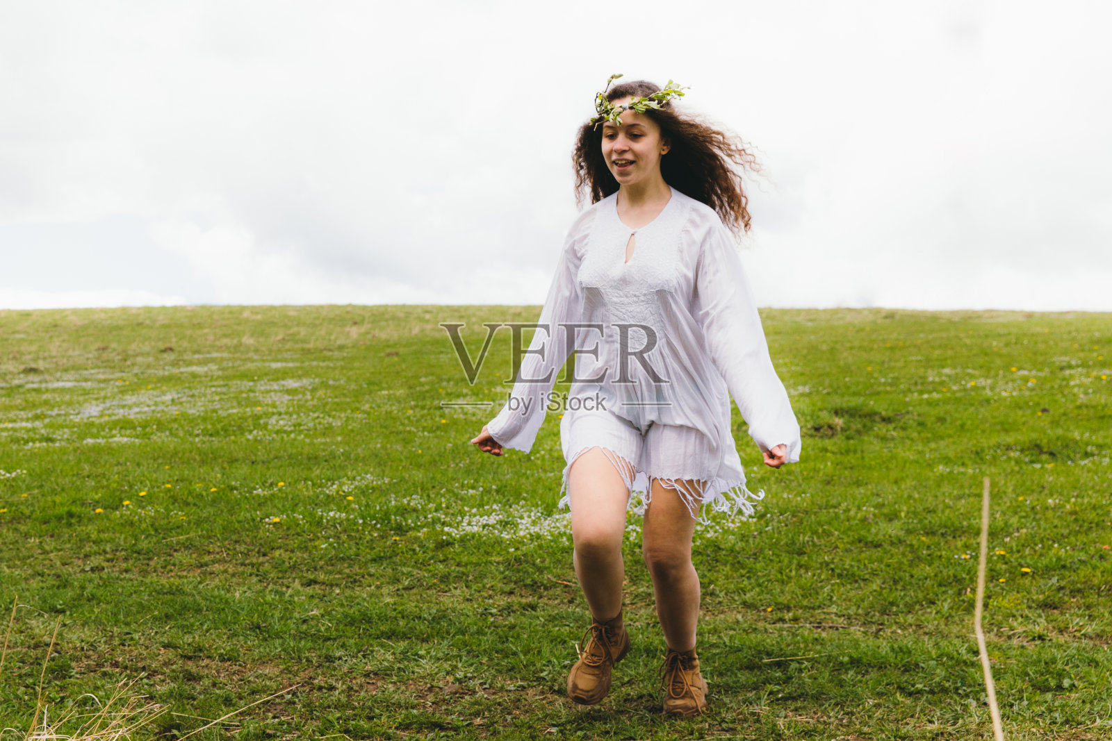 年轻快乐的女子穿着传统的白色连衣裙在美丽的草地上奔跑照片摄影图片