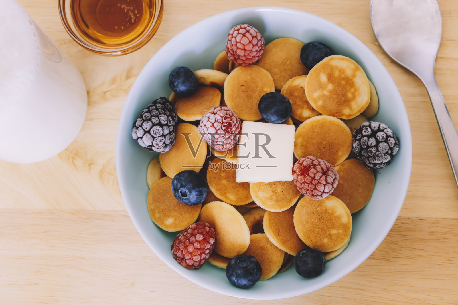 俯视图的一个蓝色碗谷物煎饼与浆果和黄油旁边的一些糖浆在木桌上照片摄影图片
