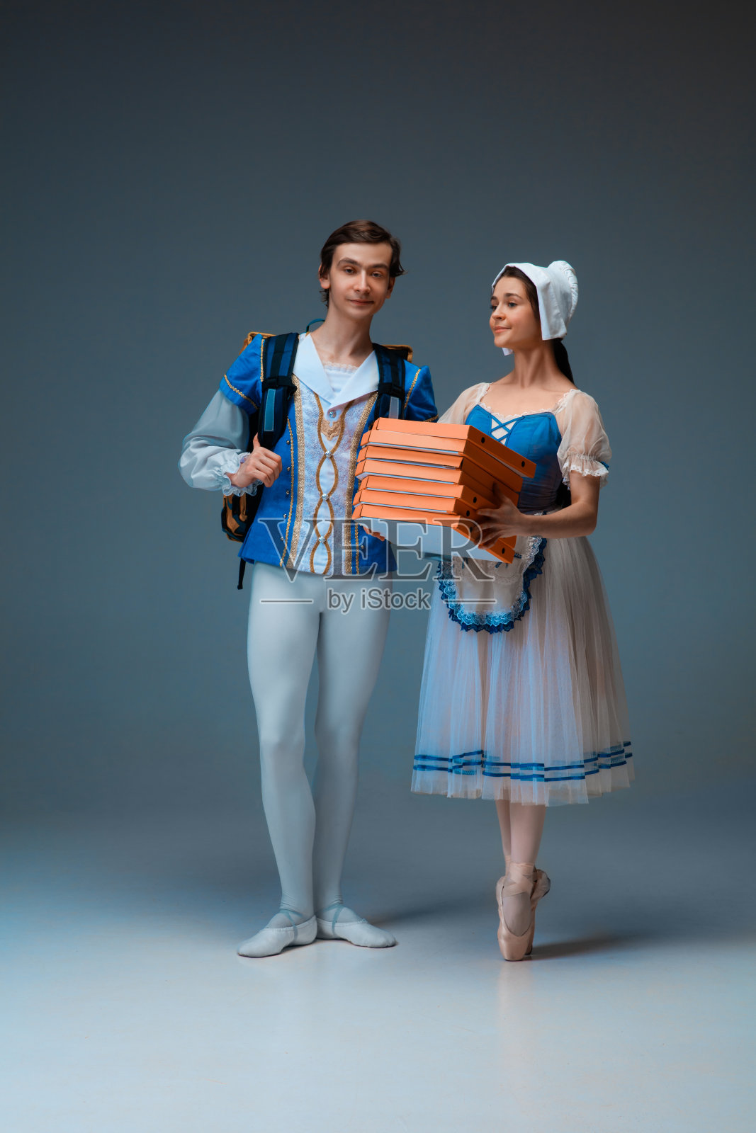 年轻优雅的芭蕾舞演员扮演灰姑娘的童话尾巴角色，像快递员一样拿着披萨匆忙赶来照片摄影图片