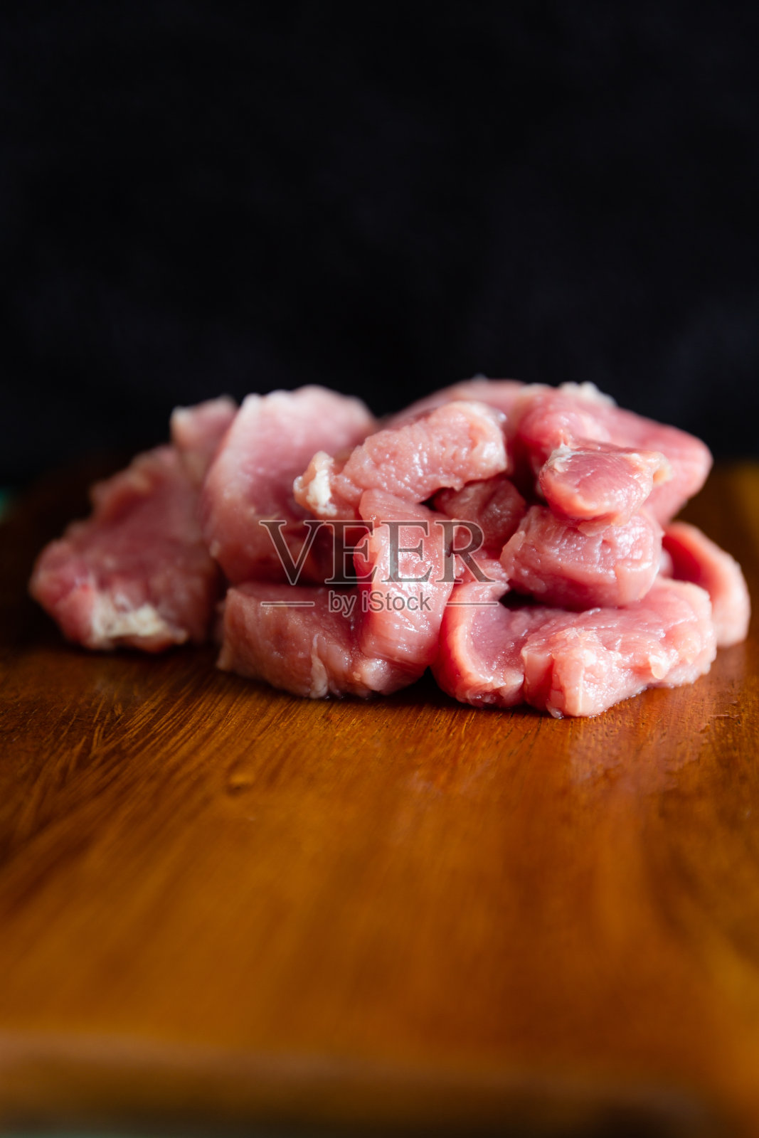 新鲜的生猪肉切片放在木头砧板上，有选择的重点。照片摄影图片