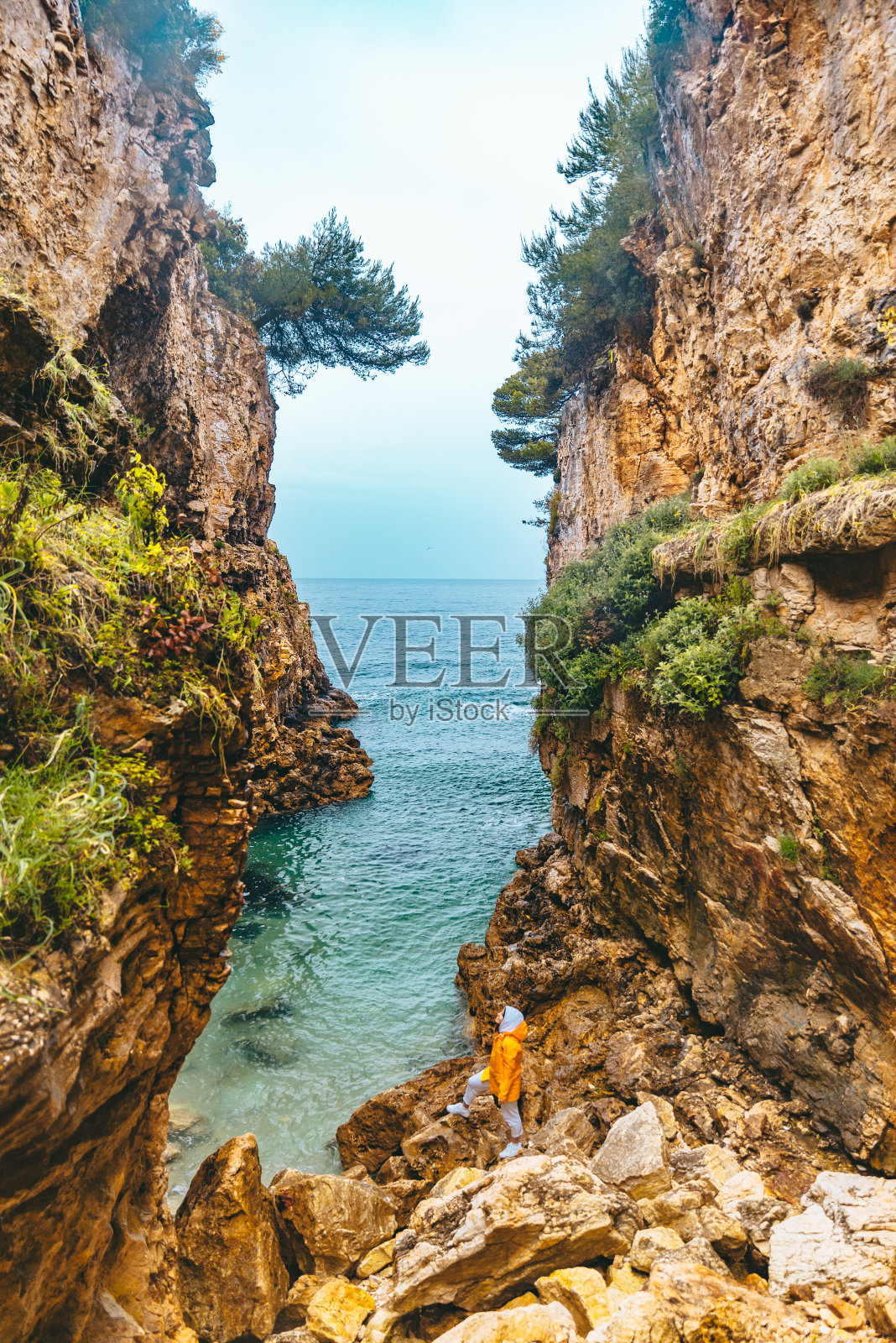 穿着雨衣的女人徒步去峡谷的海滩照片摄影图片
