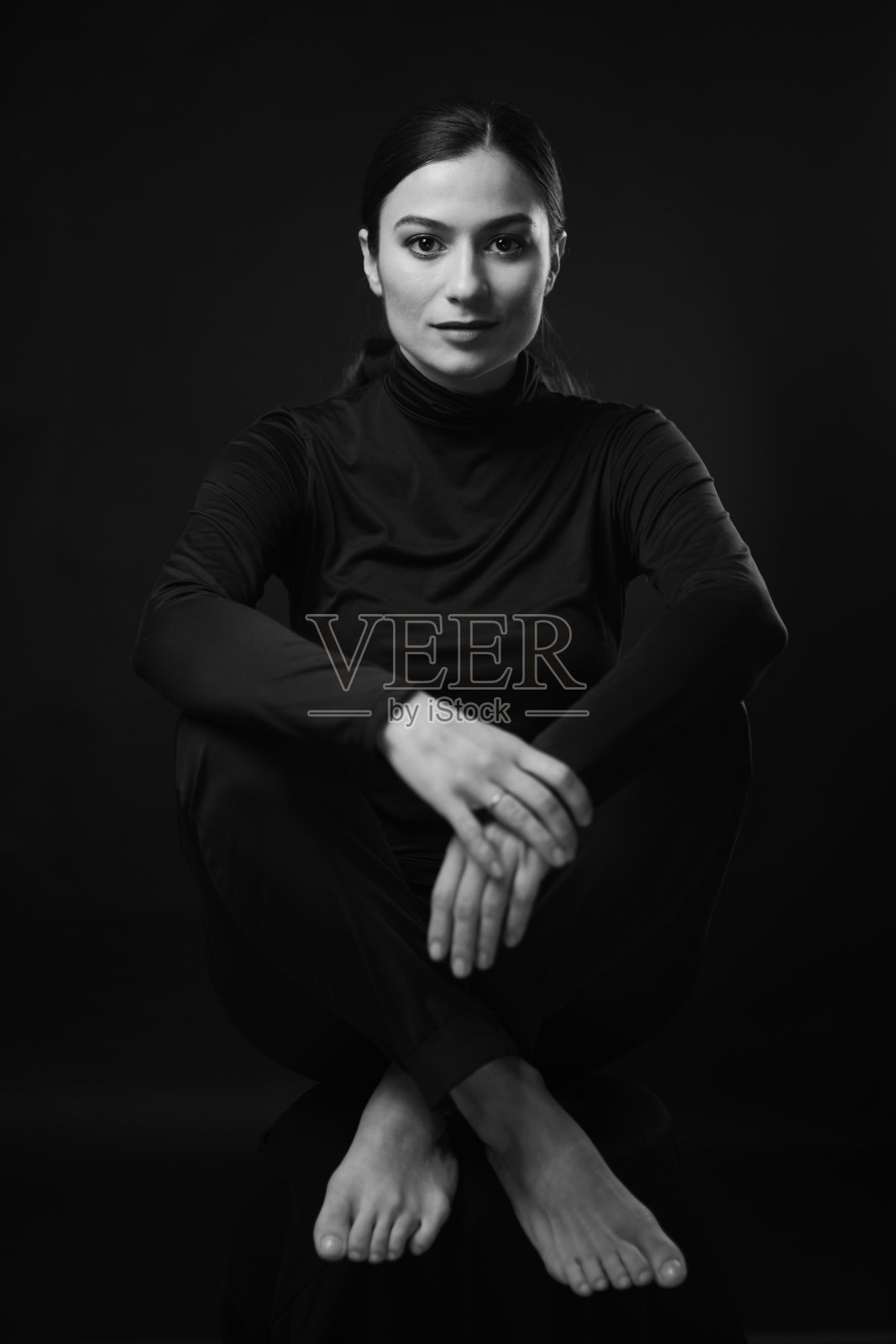 一位穿着黑色高领毛衣和黑色裤子的可爱年轻女孩坐在椅子上微笑照片摄影图片