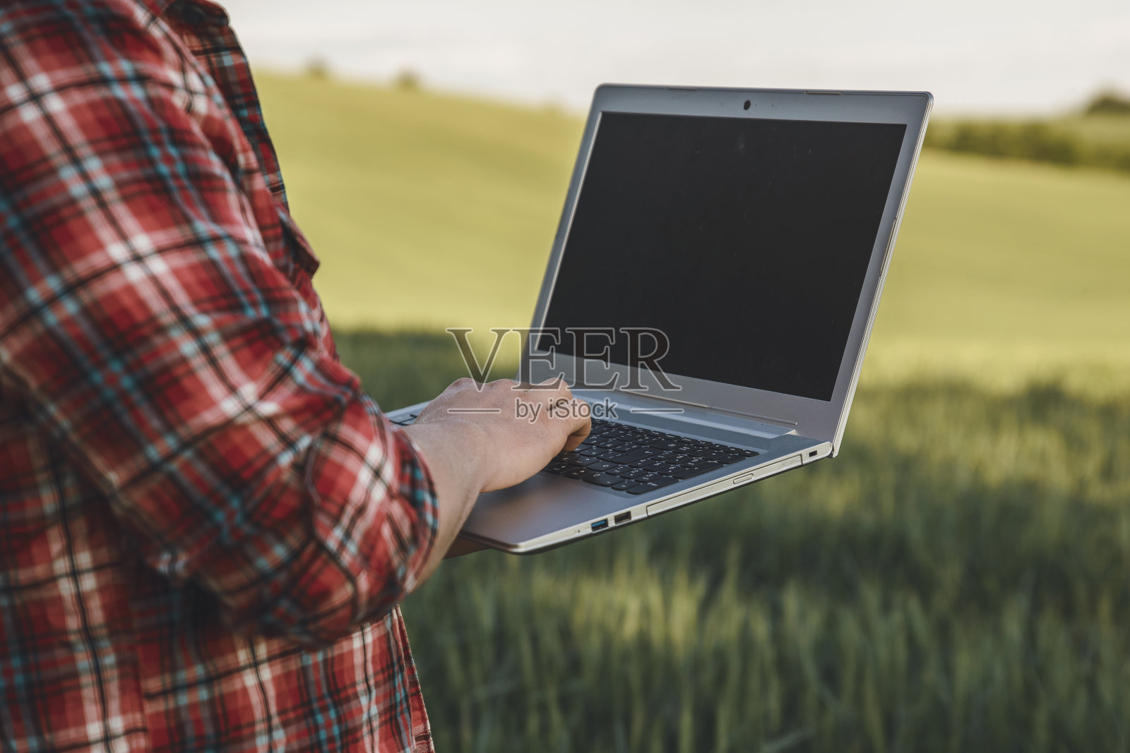 年轻的现代农民在麦田里使用笔记本电脑照片摄影图片