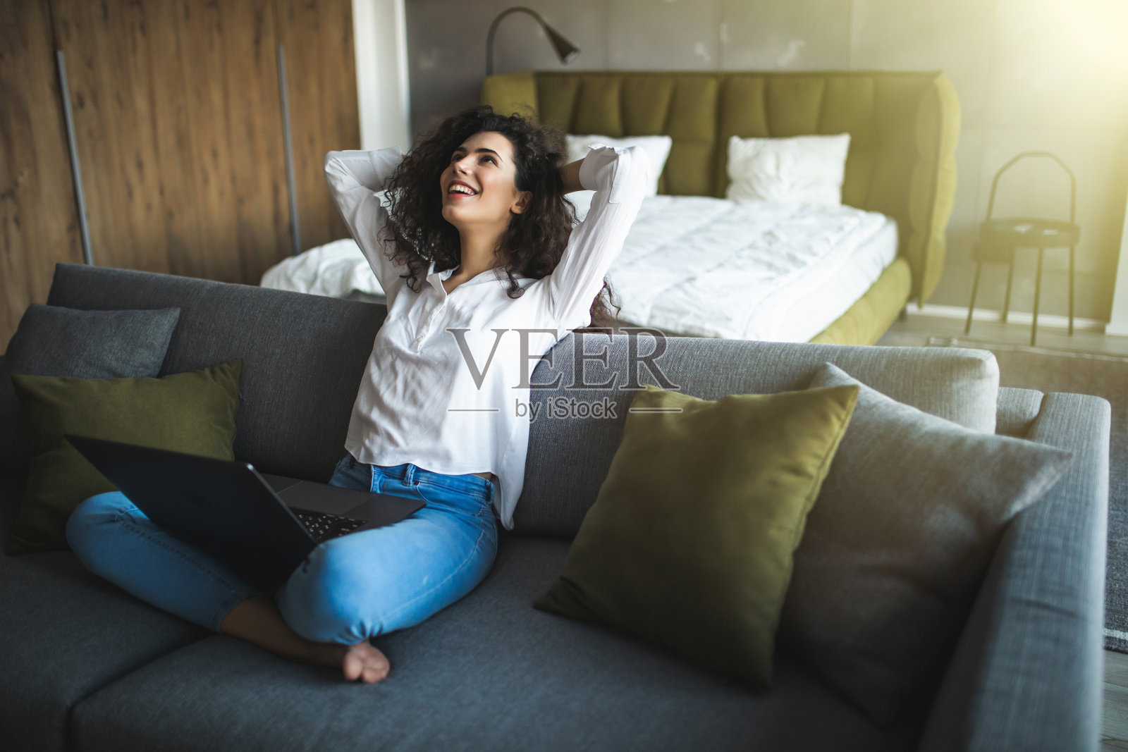 轻松的女人在豪华的家庭客厅用笔记本电脑享受工作，网上购物，查看社交网络，阅读新闻或坐在沙发上用电脑在线交流照片摄影图片