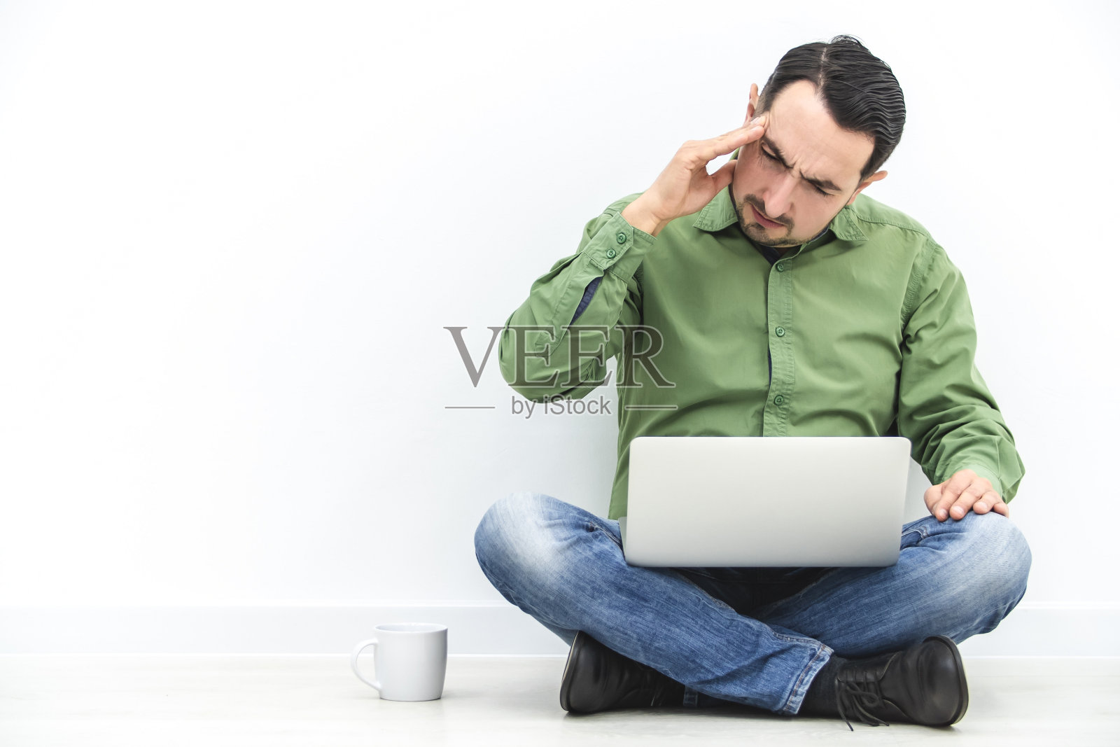 一个长胡子的白种人在笔记本电脑上工作太久，所以生病了。照片摄影图片