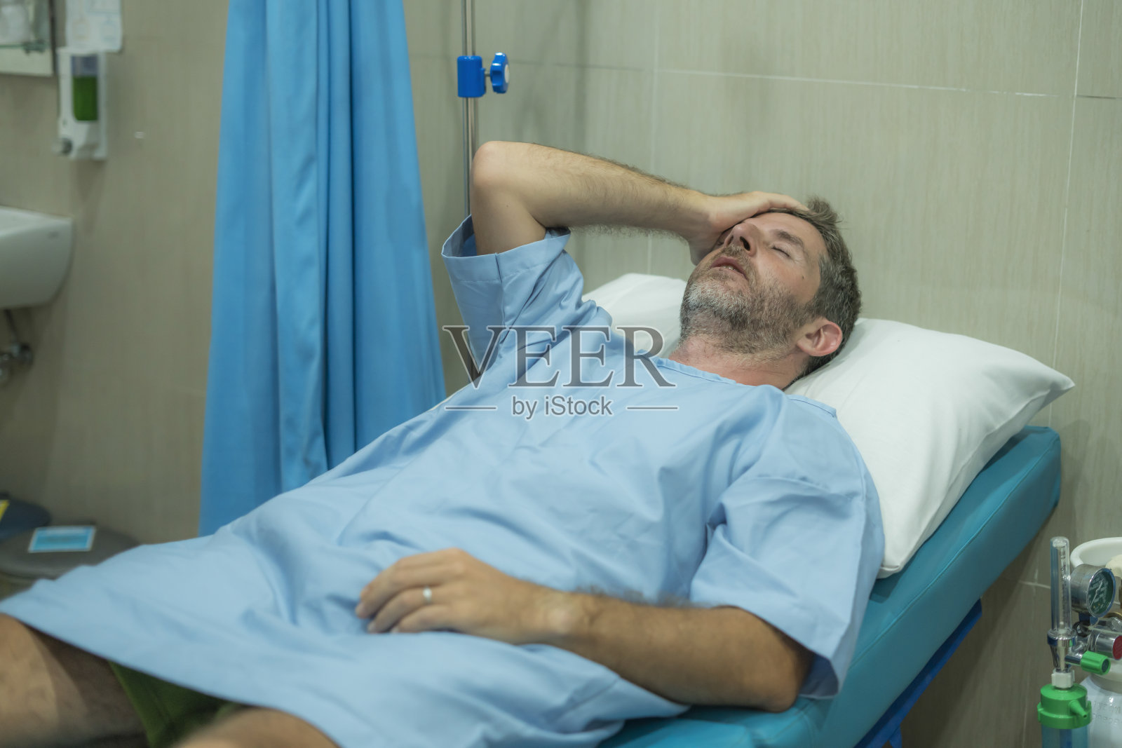 在医院的病房里，一名惊慌失措的男子痛苦地躺在床上，在遭遇事故或严重疾病后，他感到不适和压力照片摄影图片