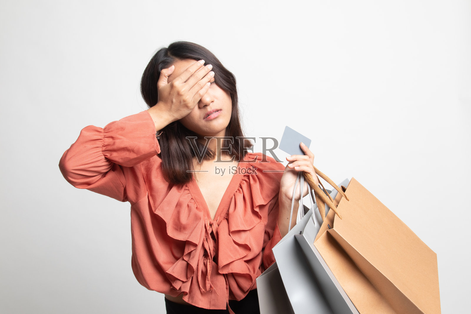 不快乐的年轻亚洲女人购物袋和信用卡。照片摄影图片