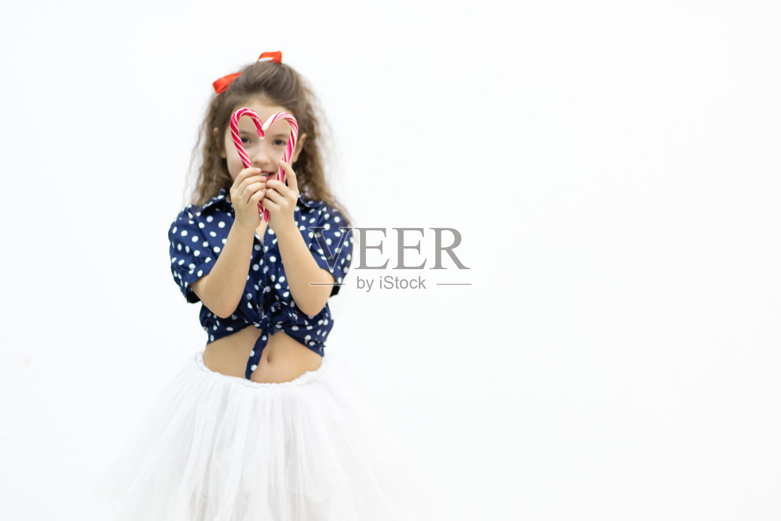 一个女孩用五颜六色的棒棒糖做了一颗心。照片摄影图片