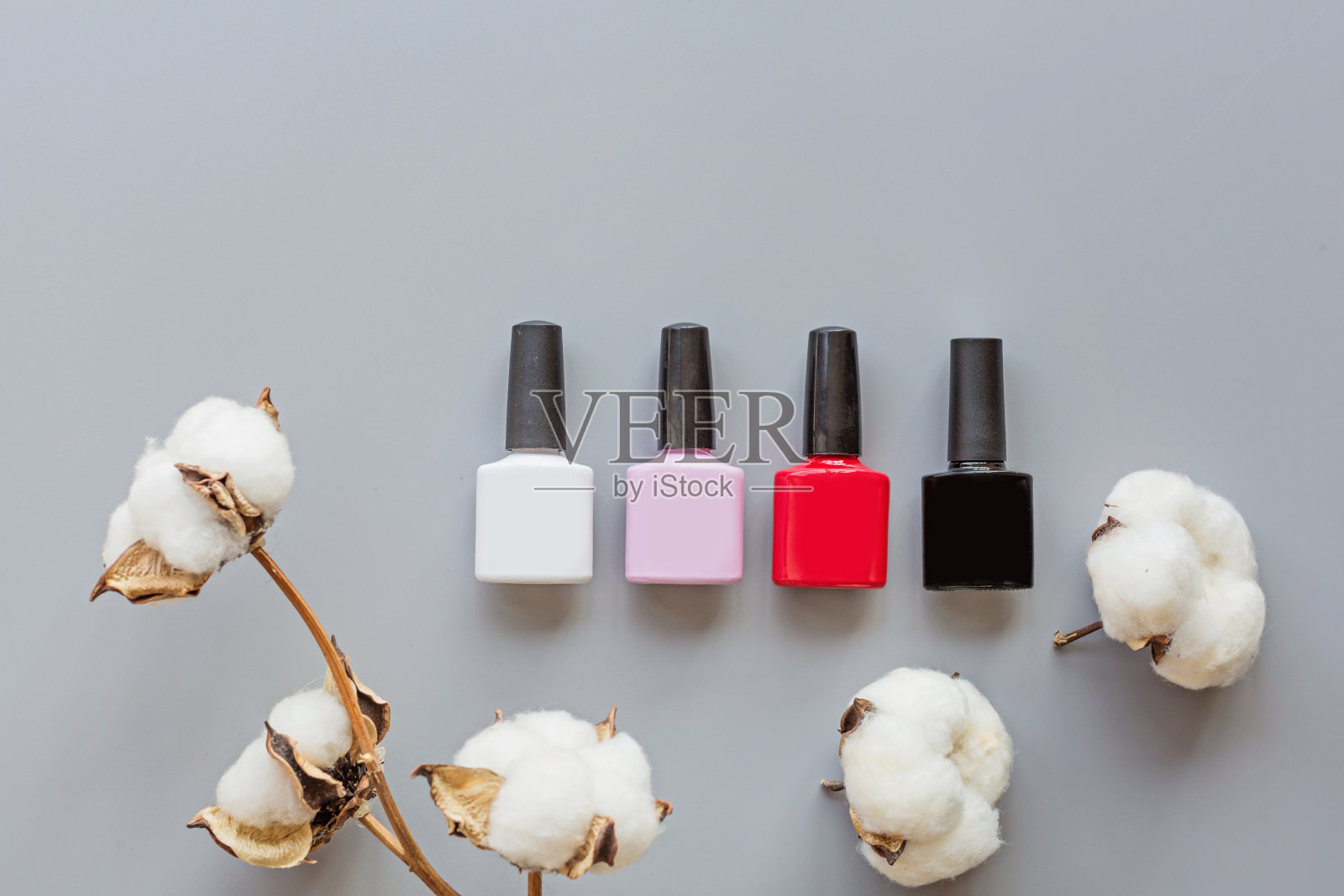时尚时尚美甲凝胶抛光在灰色背景与棉花花。最小的风格。平铺，俯视图，模拟，复制空间模板，头顶照片摄影图片
