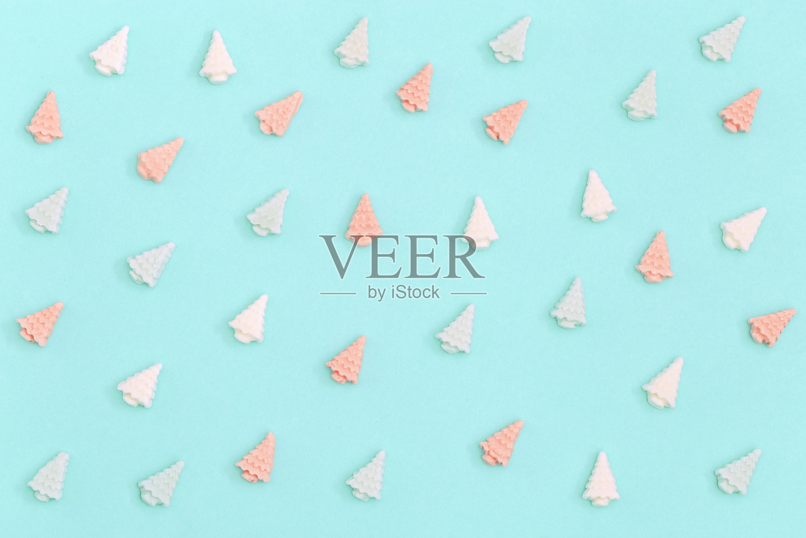 圣诞树形状的巧克力小糖果。新年或圣诞节的彩色糖果创意。柔和的颜色——薄荷色和粉红色。照片摄影图片