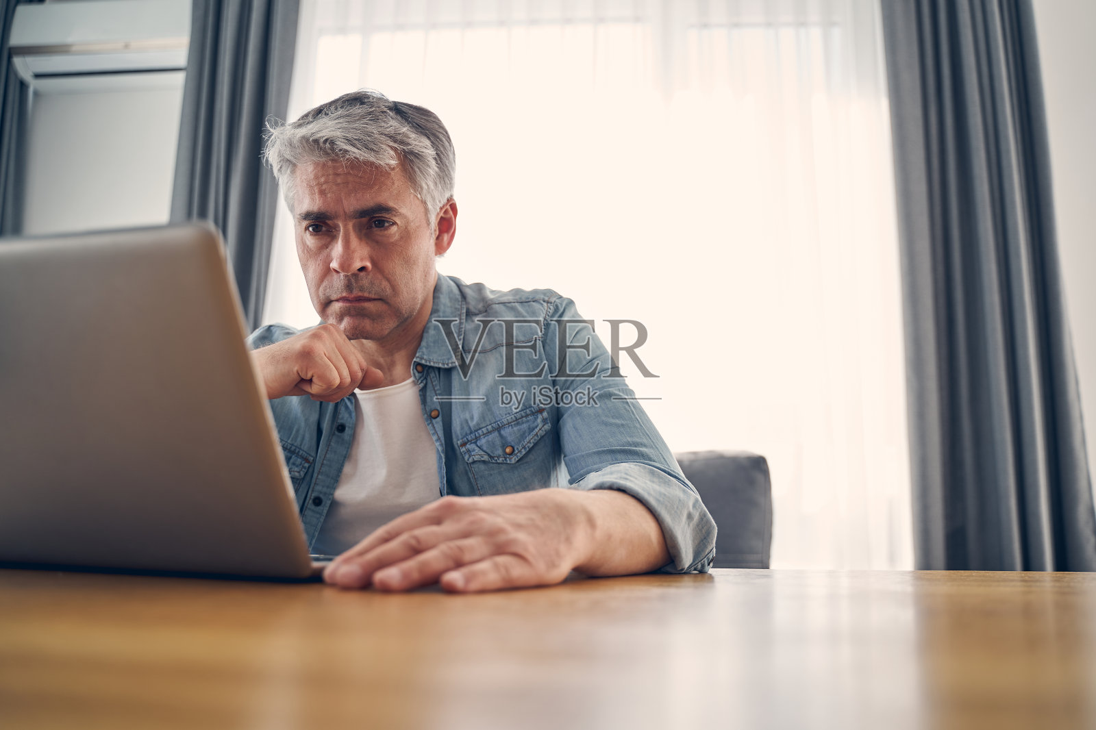 严肃的白人男性坐在桌前思考照片摄影图片