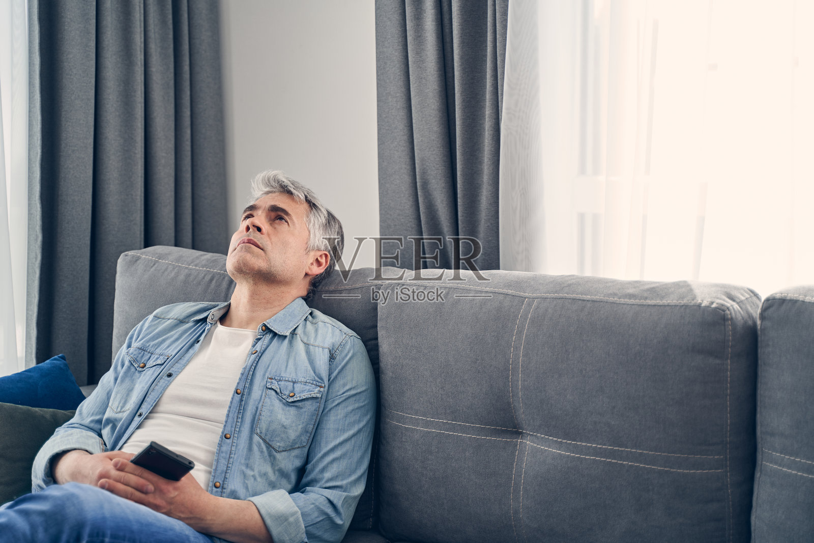 穿着牛仔裤和衬衫的男人看起来很伤心照片摄影图片