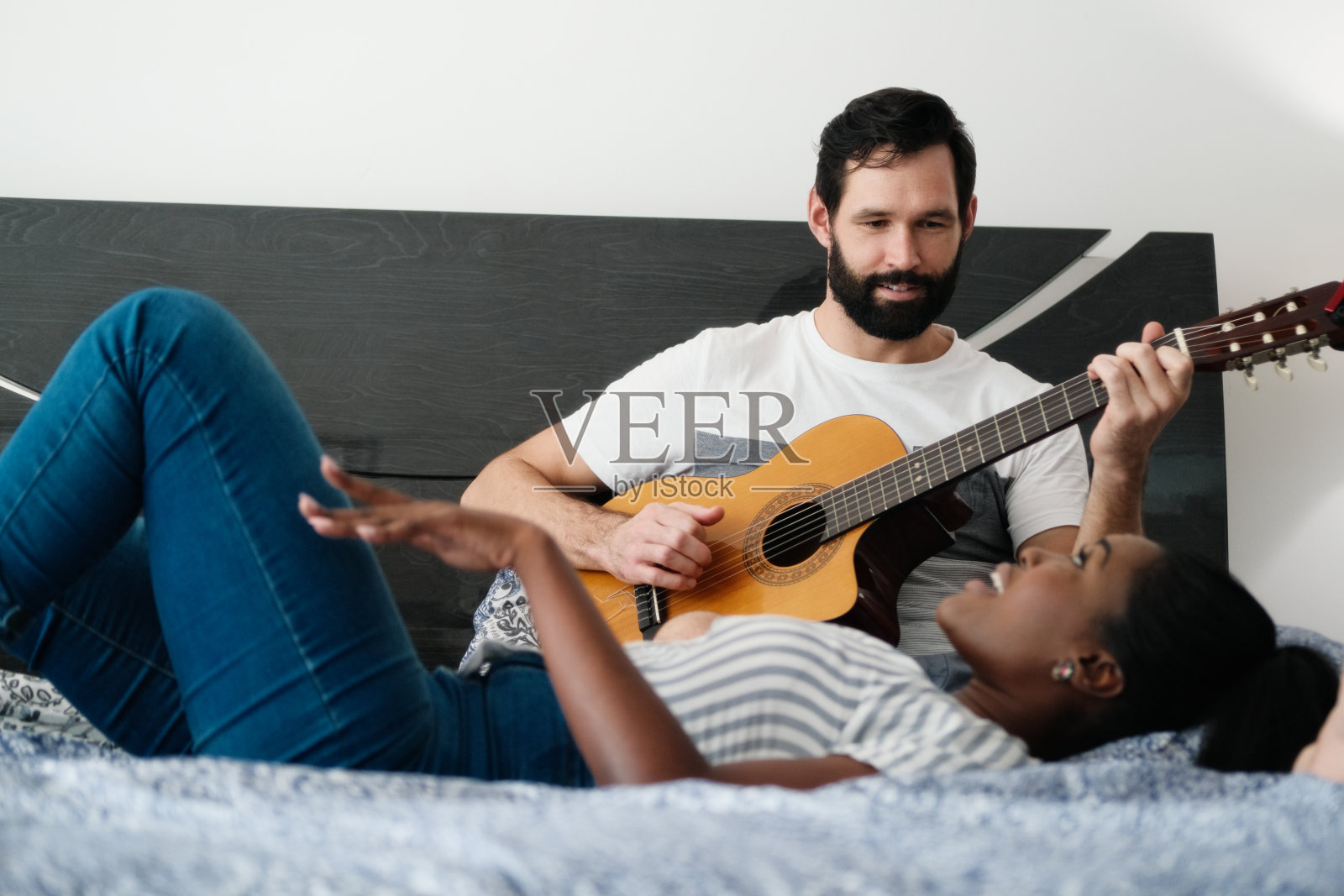 男人在卧室里弹吉他，女人在唱歌照片摄影图片