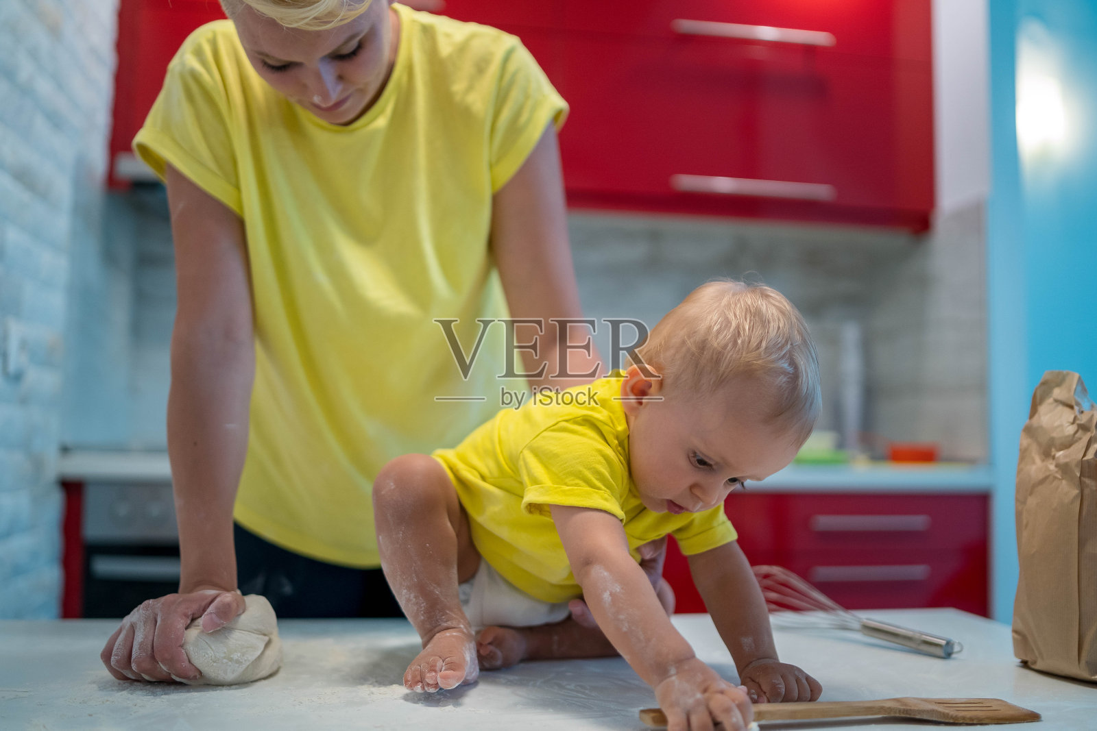 妈妈和儿子正在准备早上一起做饼干的面团。孩子在扔面粉，很高兴。照片摄影图片