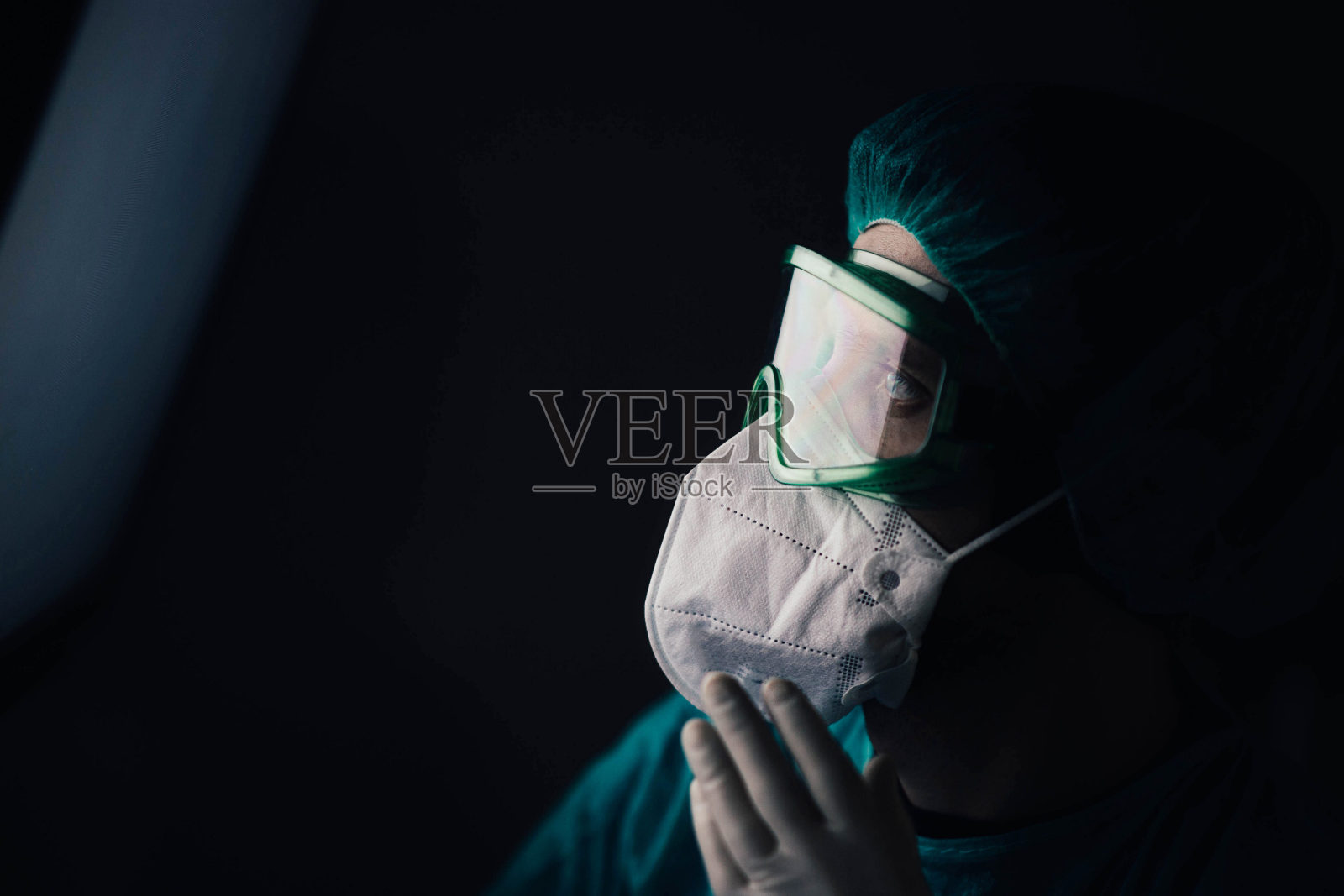 晚上，一名身穿防护服、戴着流行病学家眼镜的男子在医院里看着屏幕。照片摄影图片