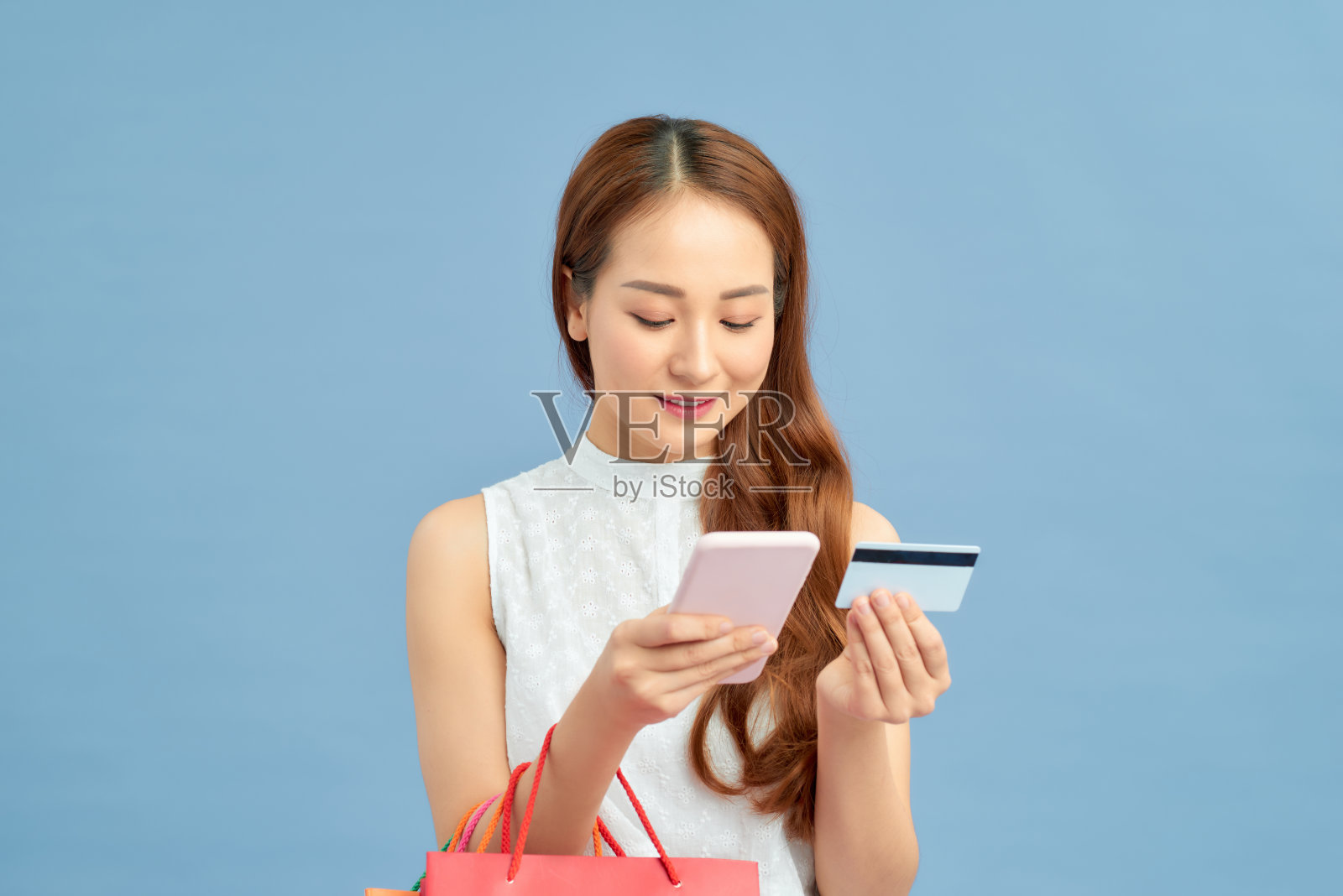 时尚的女人购物袋，信用卡和电话在蓝色的墙壁背景照片摄影图片