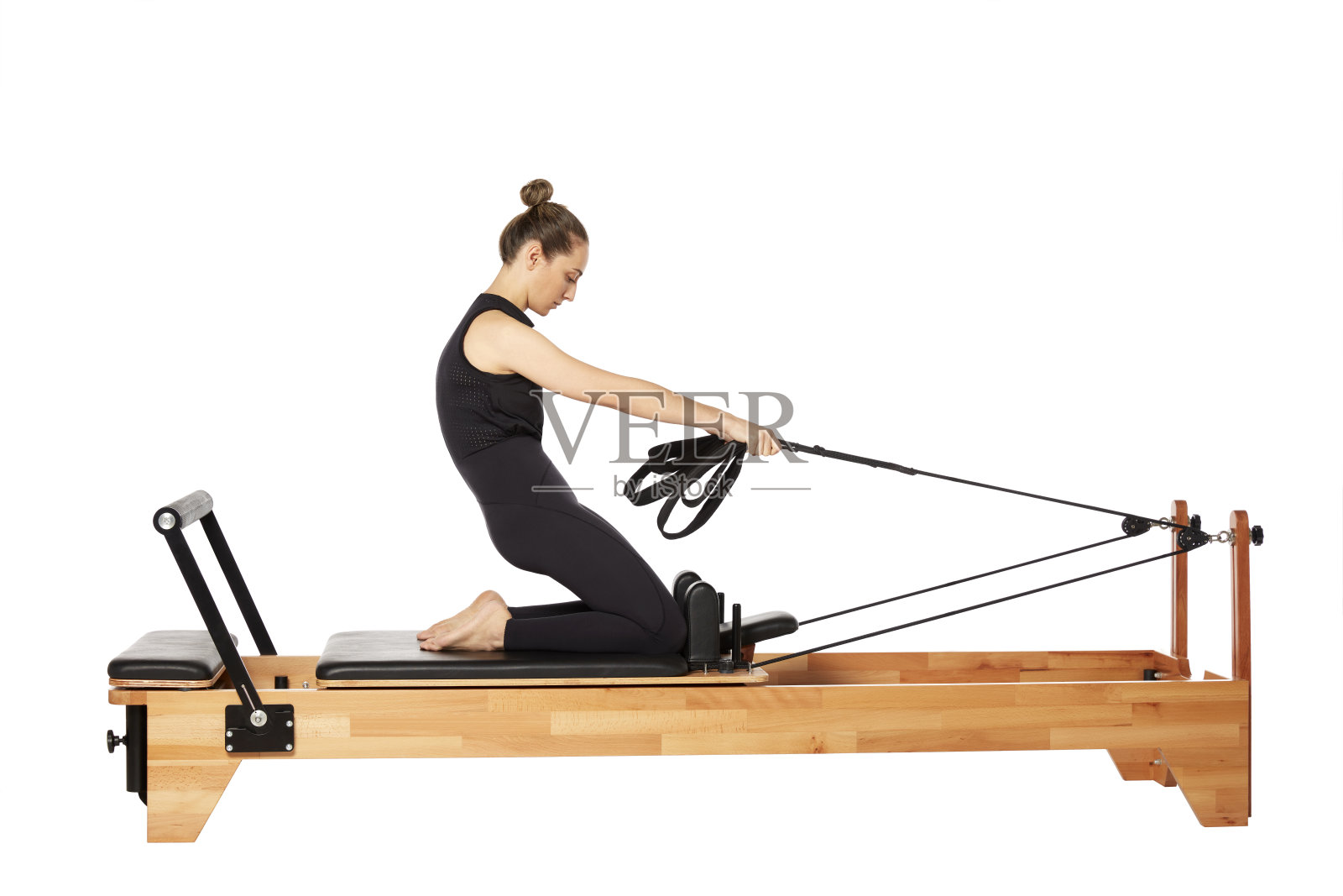 在白色背景下，年轻女子在普拉提机上锻炼照片摄影图片