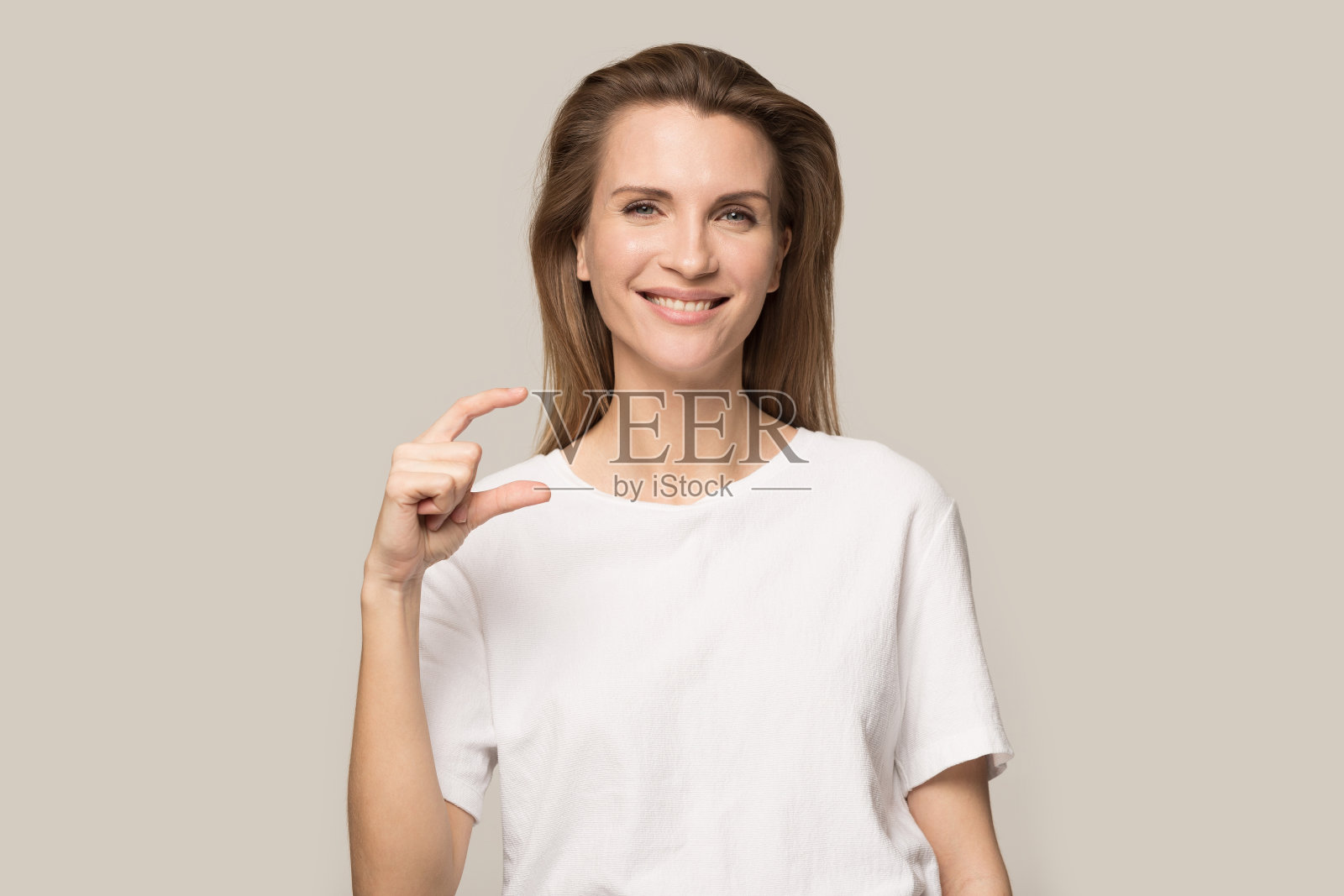 微笑的年轻女子显示小尺寸手势与手指照片摄影图片