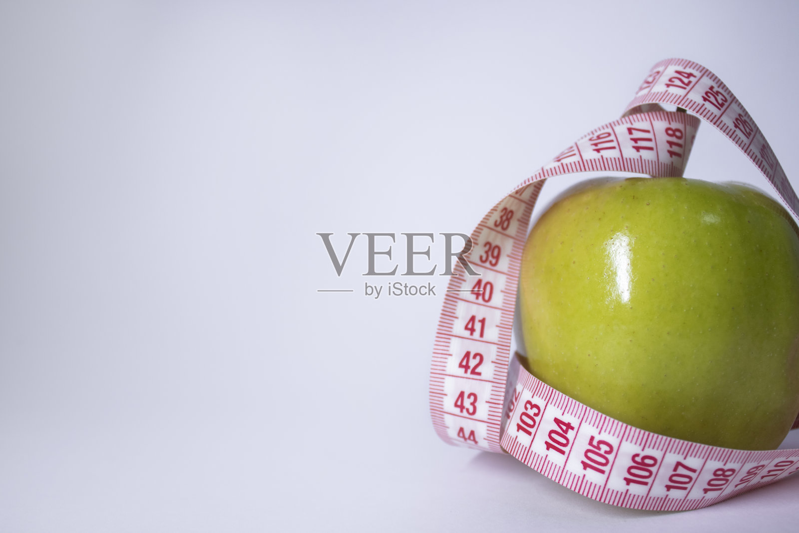 红卷尺盖青苹果。饮食与健康生活、减肥理念。前视图。副本的空间。孤立。白色背景照片摄影图片