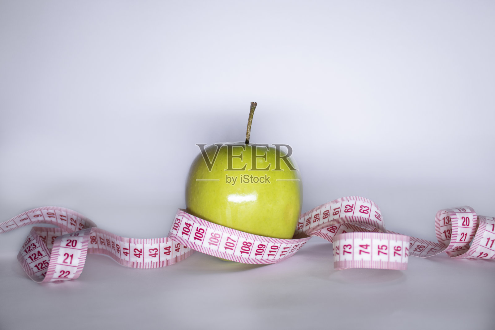 红卷尺盖青苹果。饮食与健康生活、减肥理念。前视图。副本的空间。孤立。白色背景照片摄影图片