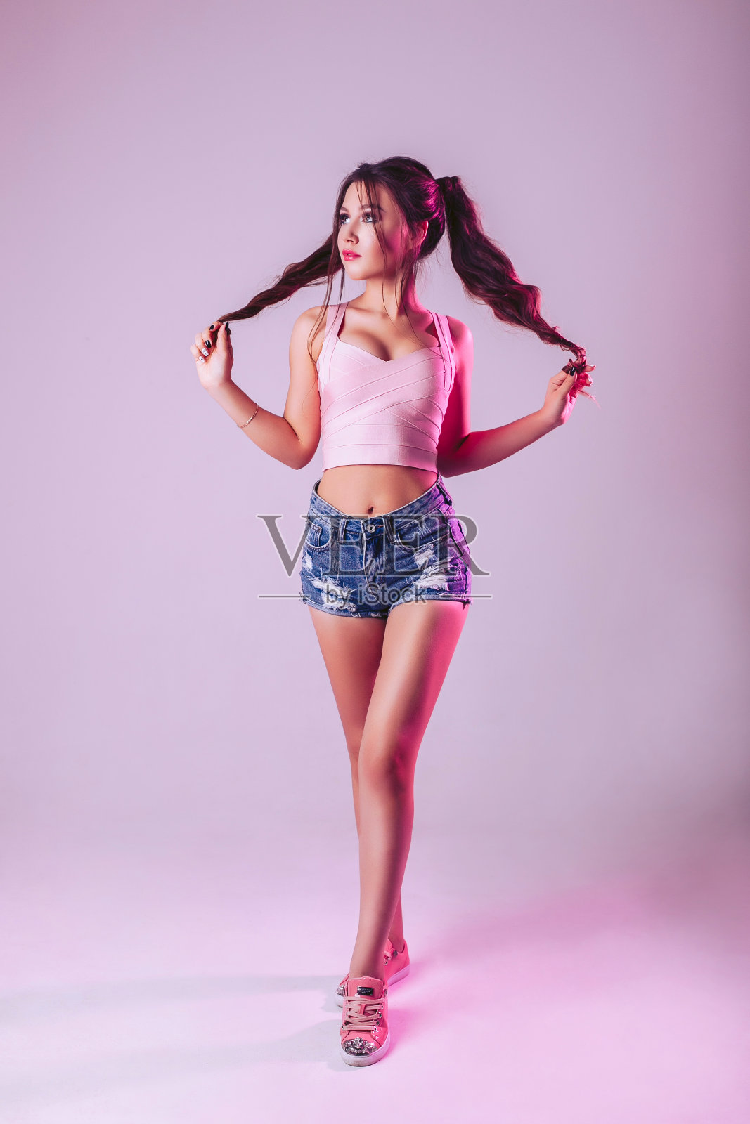 画室里一个浅紫色背景的美女。用手抓住头发照片摄影图片