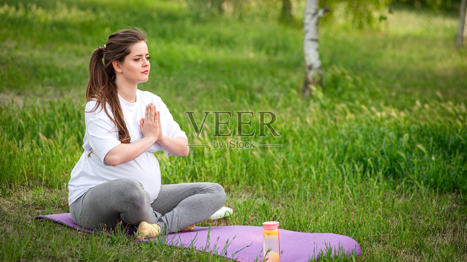 健康孕妇在户外做瑜伽。照片摄影图片