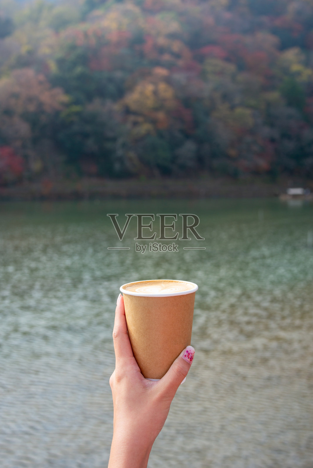 年轻女子手拉手拿出咖啡一次性纸杯旁边的一条河与秋叶景观照片摄影图片