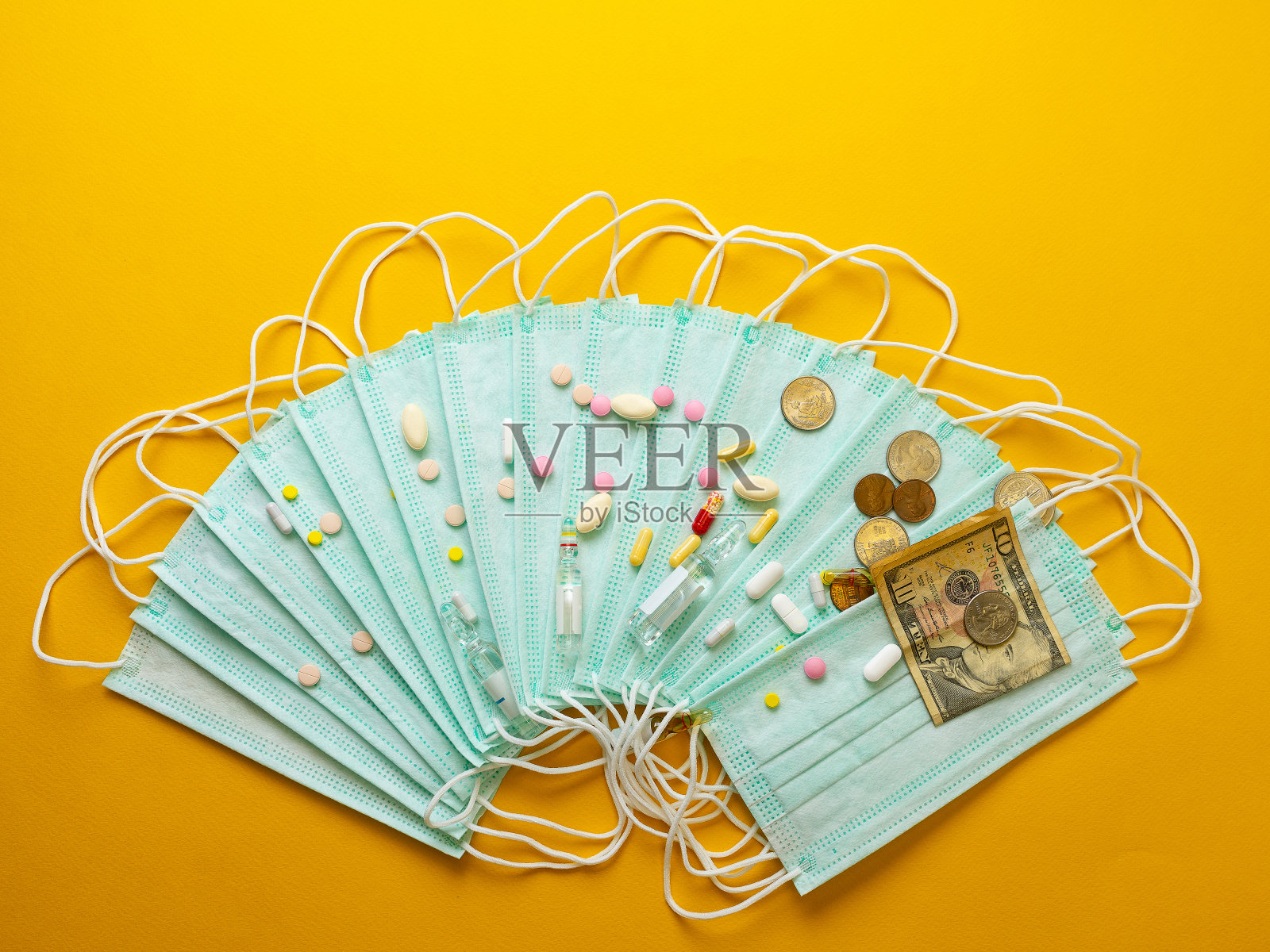 医用口罩销售。医用防护口罩和不同类型的药片旁边的钱的黄色背景。医学中的通货膨胀概念。照片摄影图片