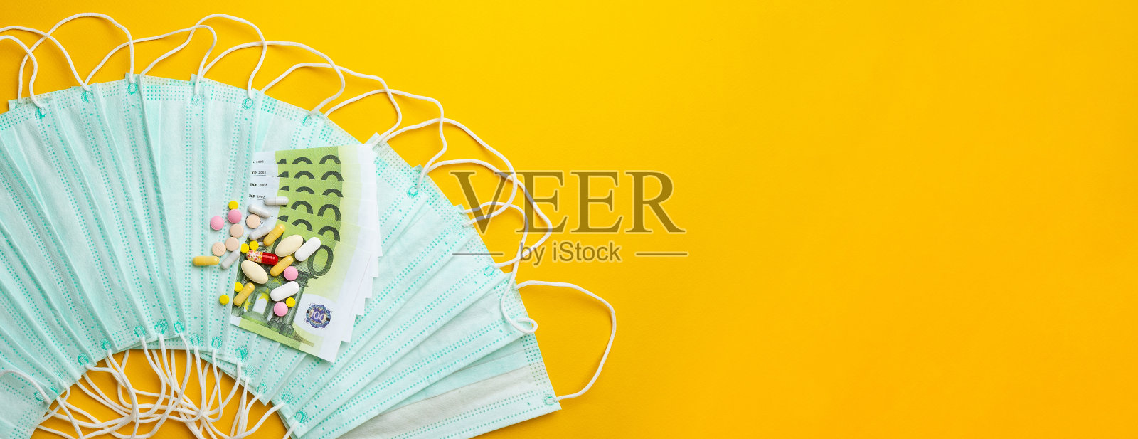 医用口罩销售。医用防护口罩和不同类型的药片旁边的钱的黄色背景。冠状病毒的概念。covi - 2019照片摄影图片