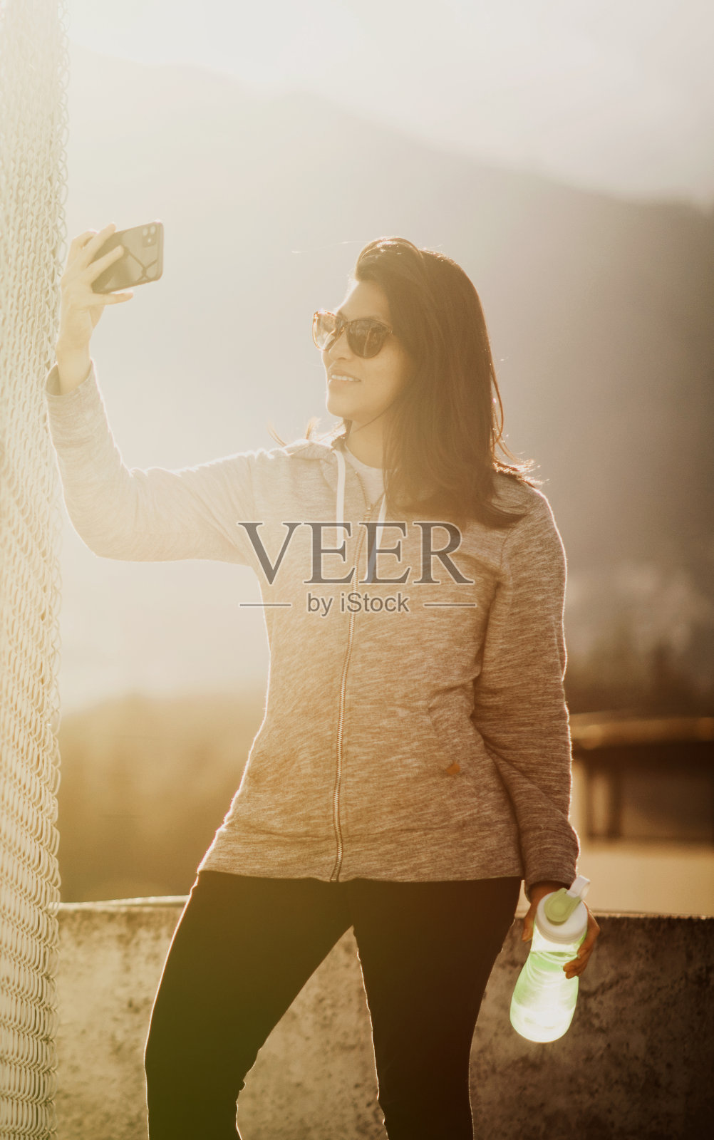 可爱的西班牙女人穿得很运动，在她的电话照片摄影图片