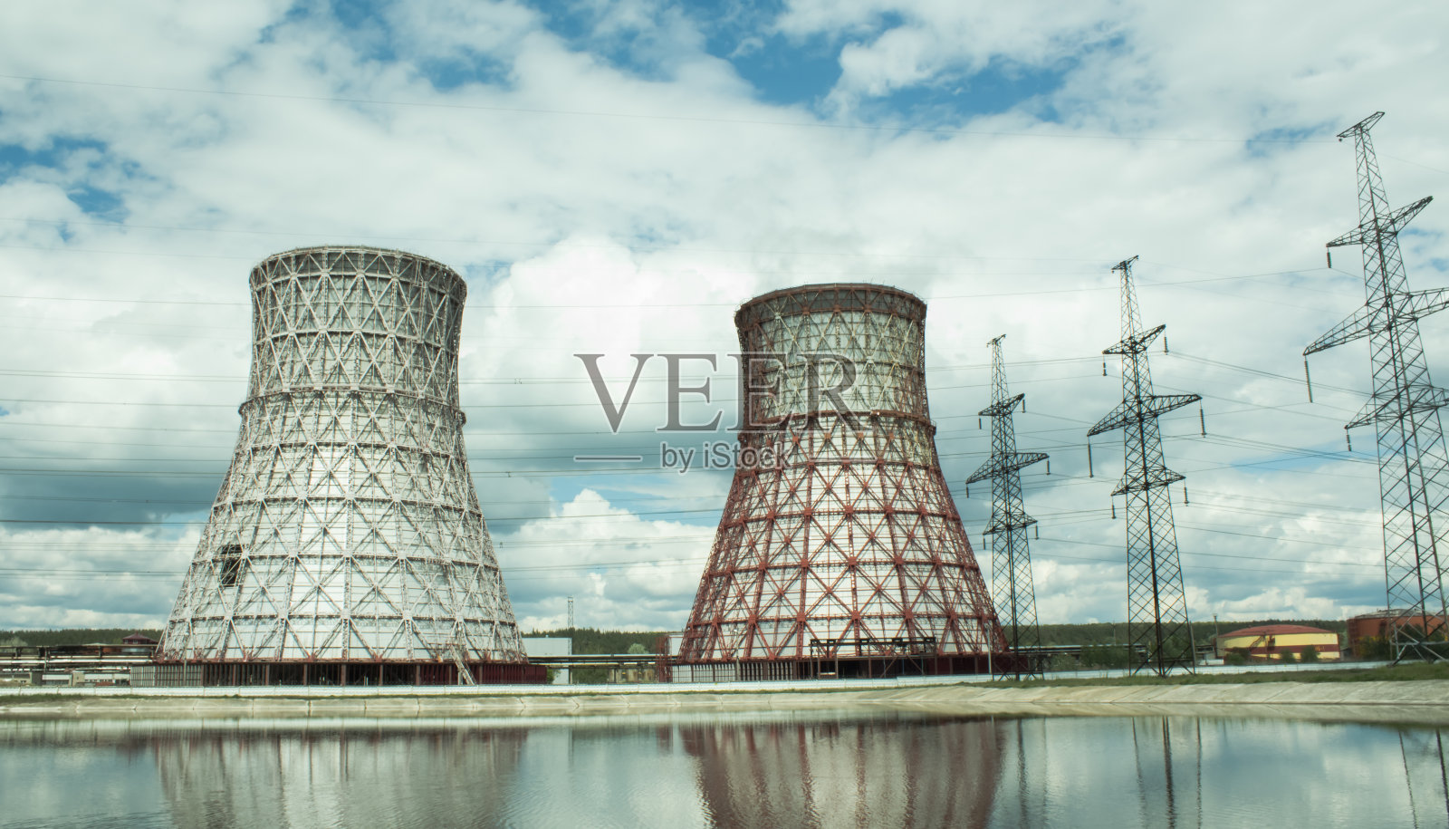 发电厂和冷却塔的观点。烟从运行中的发电站的冷却塔里冒出来。热电电站的冷却塔反映在技术水库中。照片摄影图片