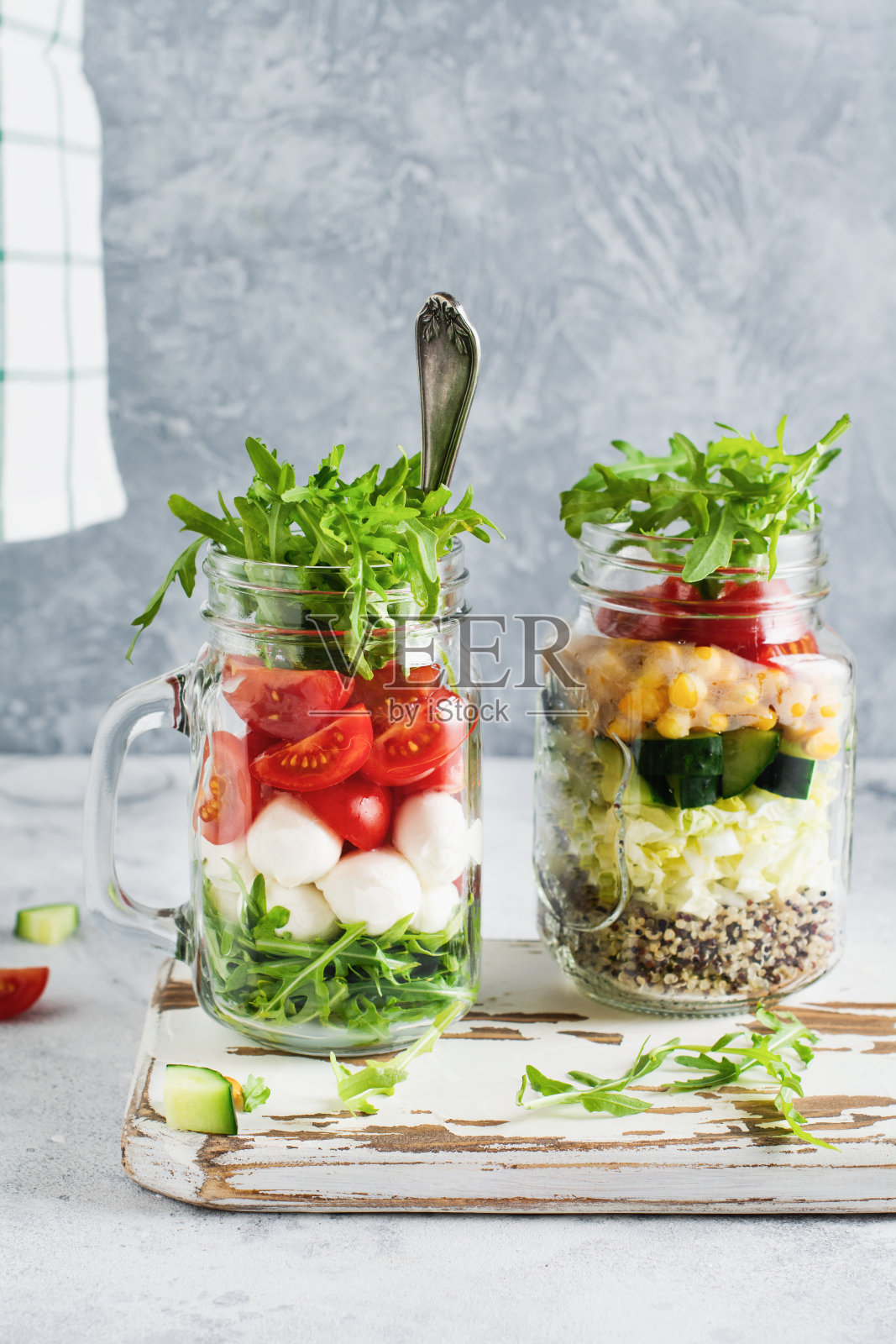 一种用芝麻菜、马苏里拉奶酪和樱桃番茄做成的罐装意大利沙拉，作为午餐摆在桌上。有选择性的重点。照片摄影图片