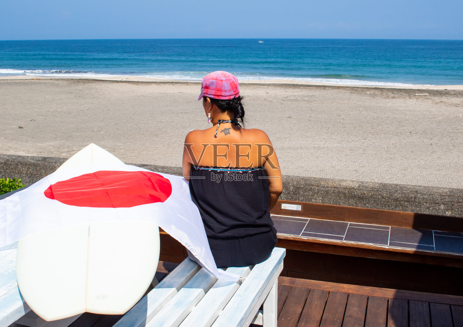 一名日本女子在千叶海滩上举着冲浪板和日本国旗照片摄影图片