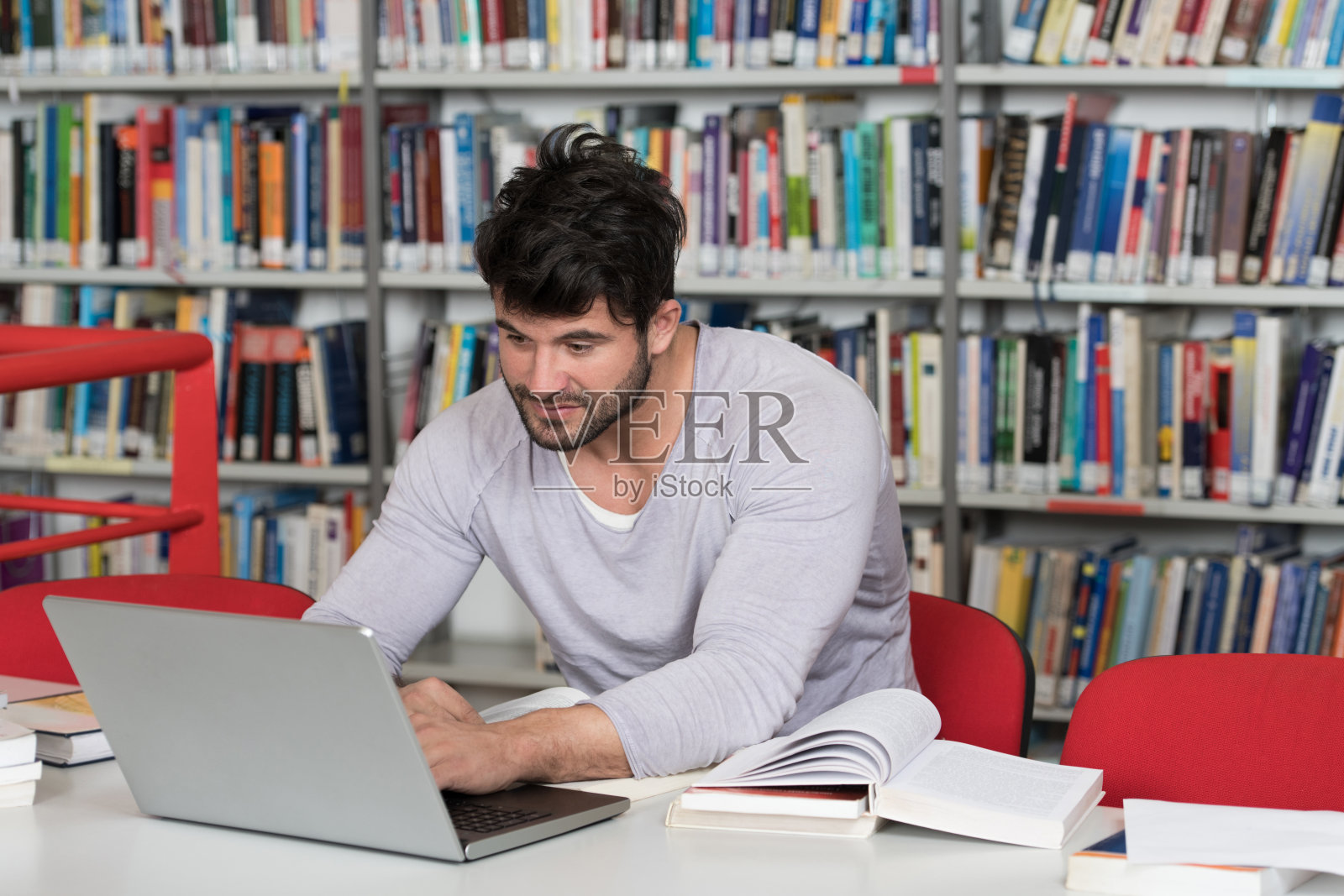 男学生在大学图书馆用笔记本电脑打字照片摄影图片