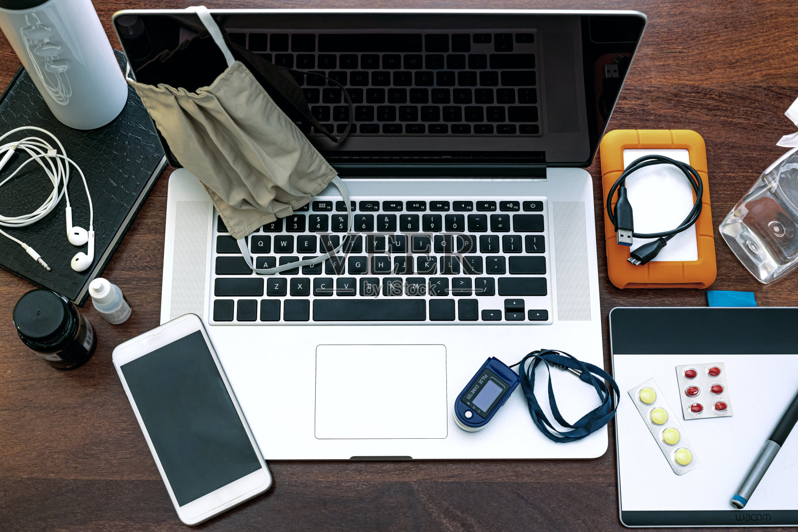 黑色笔记本电脑屏幕的视图，工作设备，外科口罩和脉搏血氧计。照片摄影图片