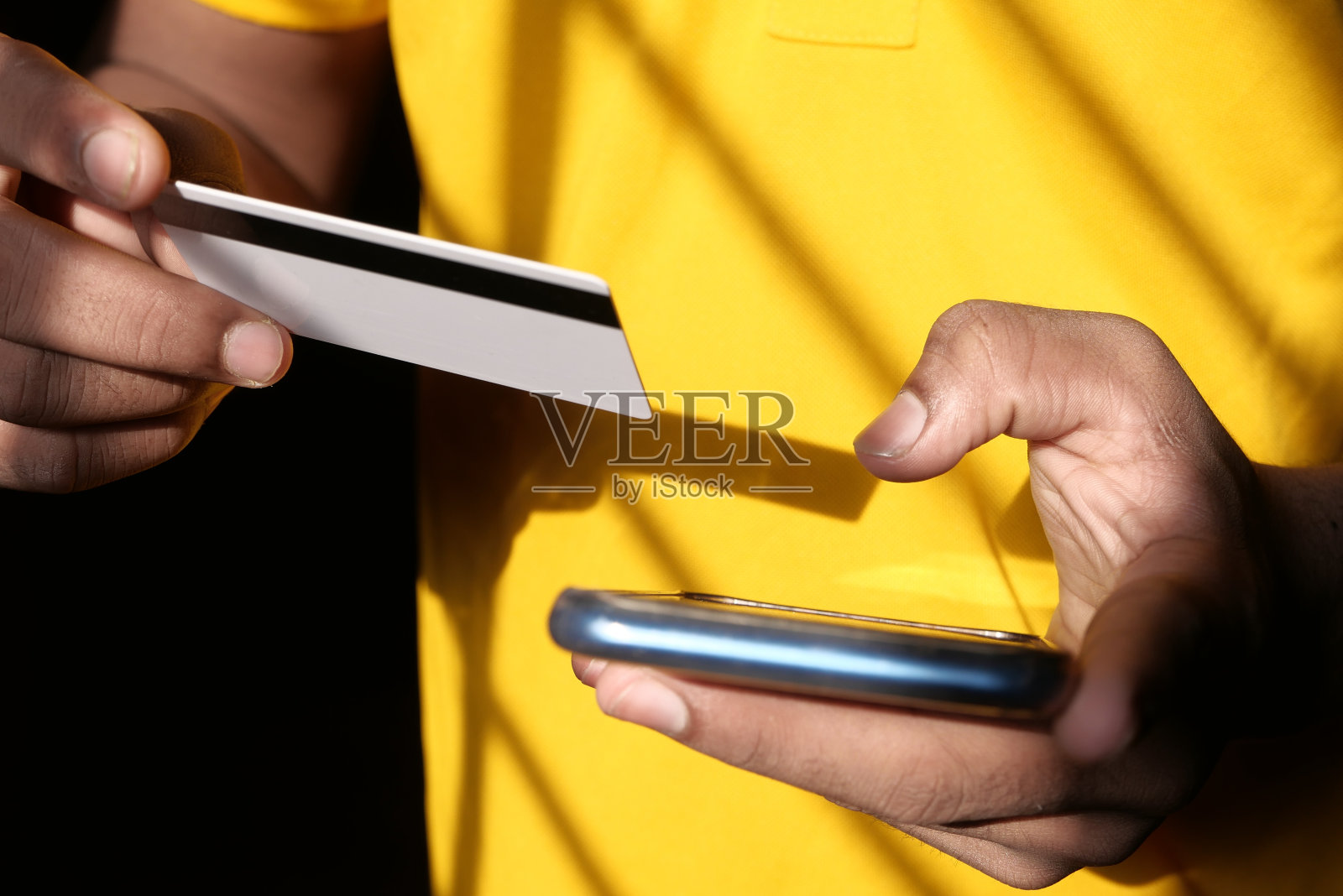 男子手持信用卡，用智能手机在线购物照片摄影图片