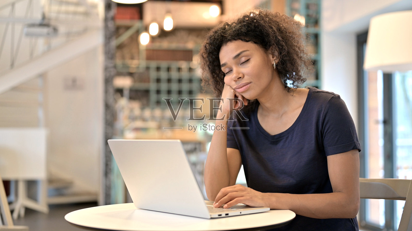 疲倦的年轻非洲女人睡在咖啡馆照片摄影图片
