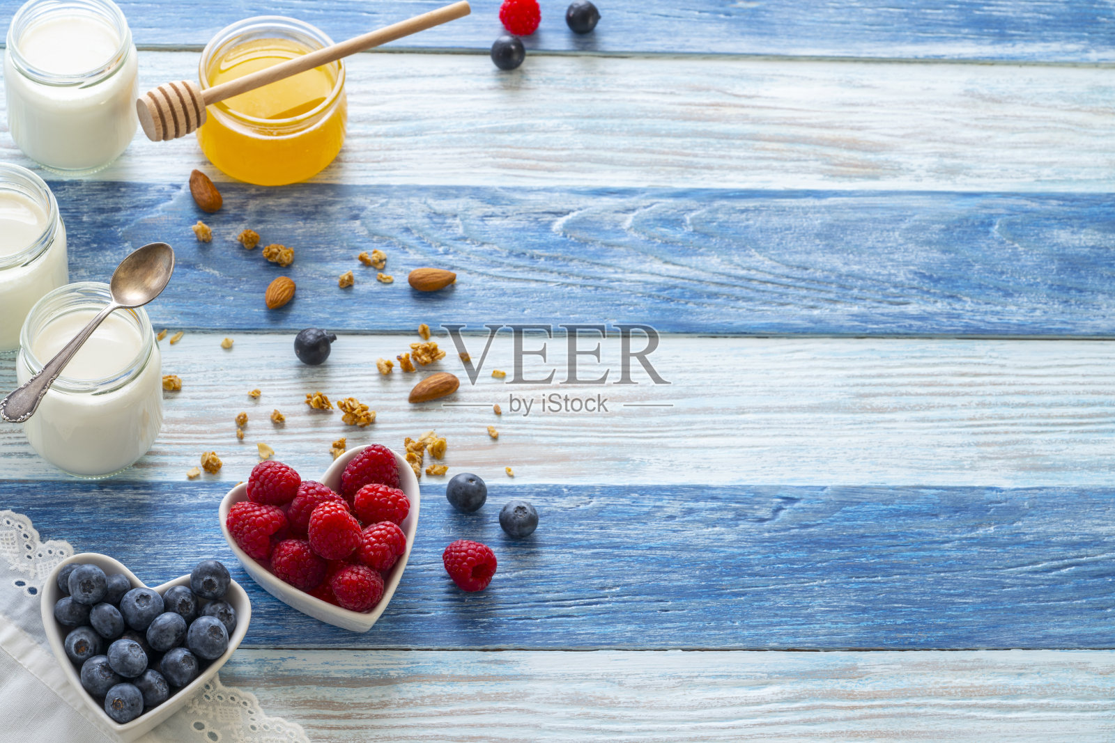 自制酸奶酸奶在玻璃罐与薄荷叶浆果格兰诺拉麦片和蜂蜜在蓝色照片摄影图片