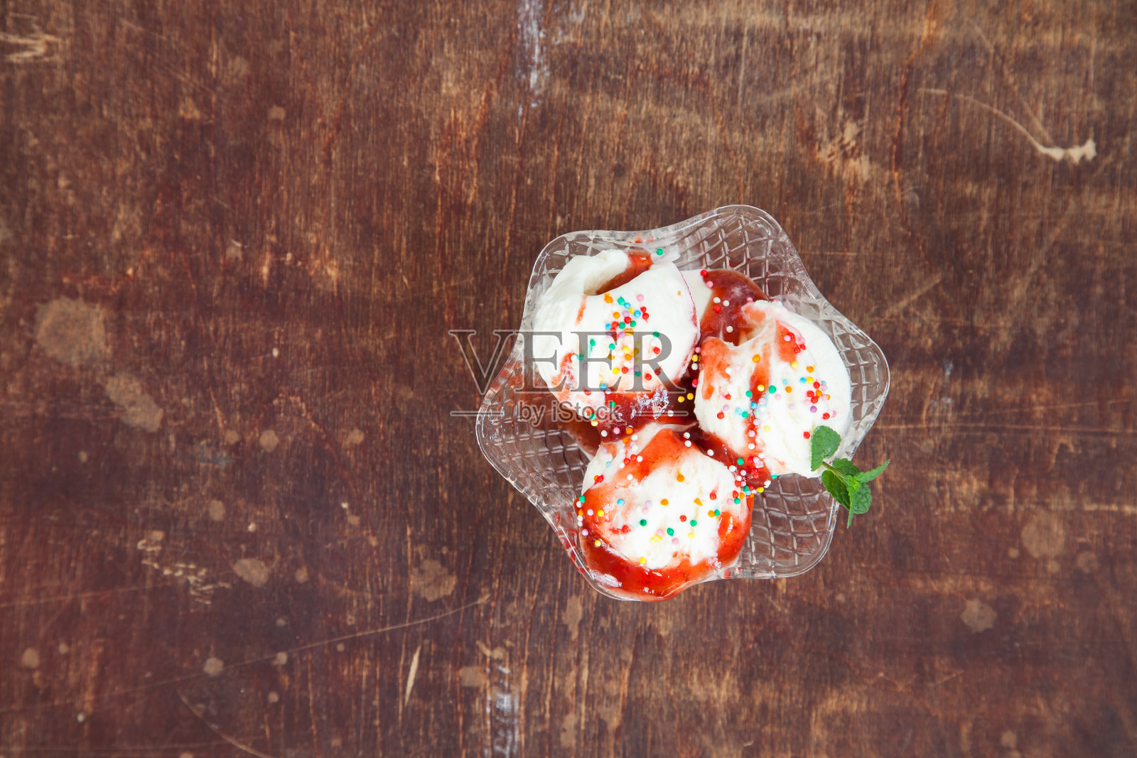 冰淇淋与草莓糖浆在一个冰淇淋碗在桌子上，选择性的焦点照片摄影图片