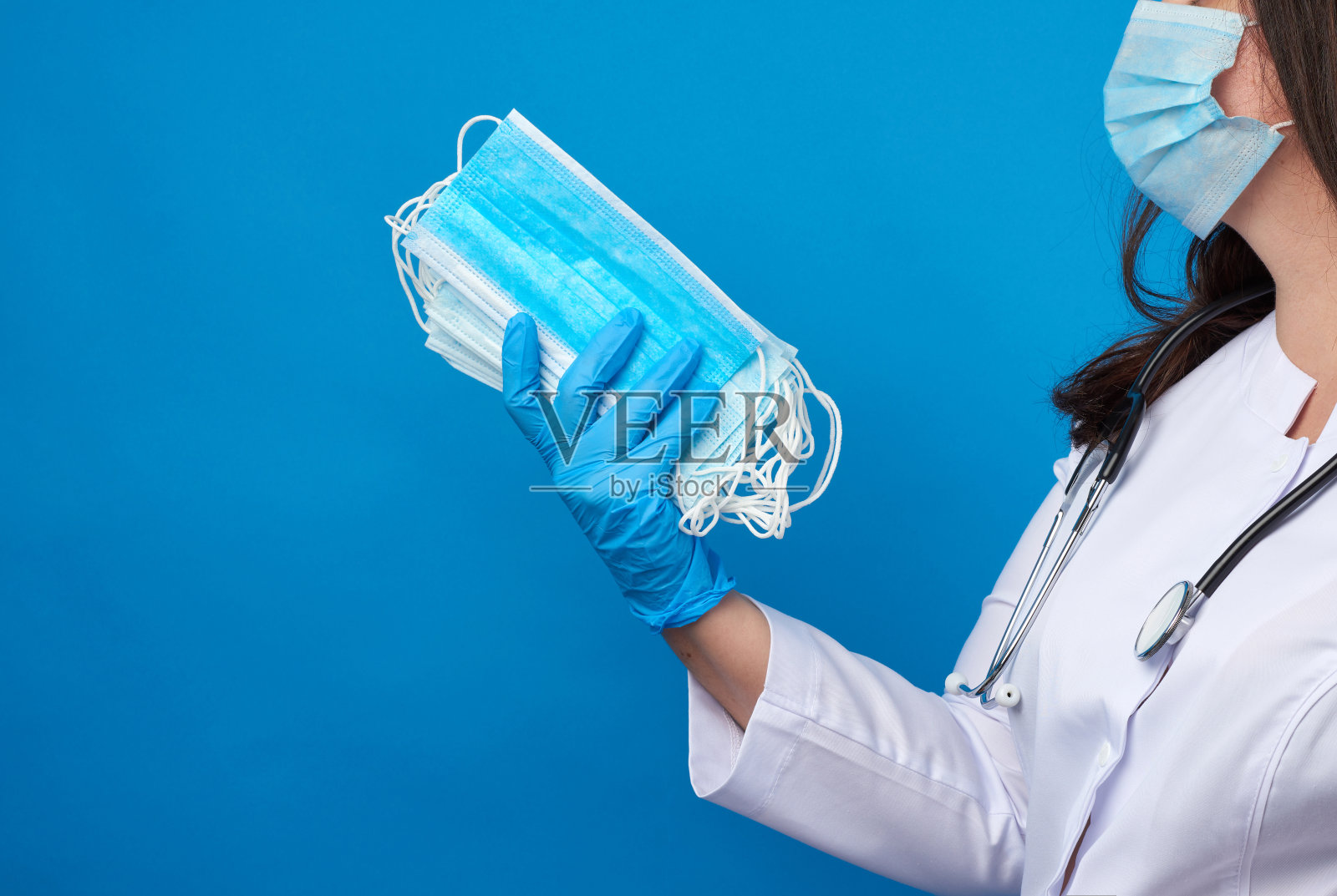 医生身穿白大褂，戴着口罩，手里拿着一叠一次性防护口罩照片摄影图片