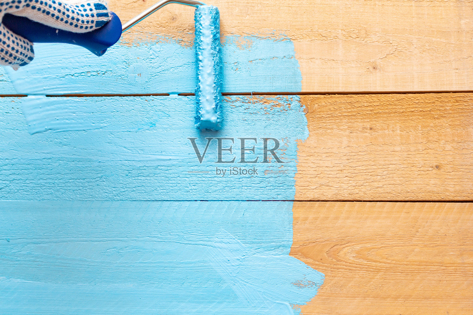 用油漆滚筒在绿色漆盘上画上蓝色的漆，在木制的背景上DIY照片摄影图片