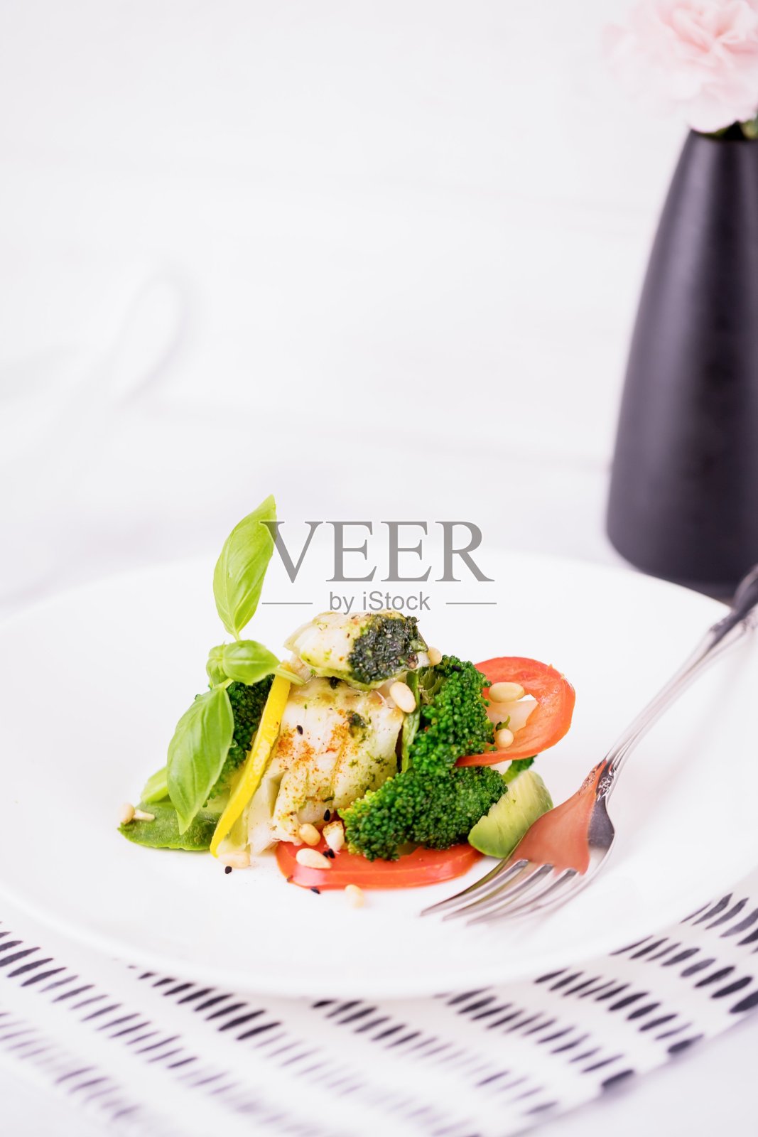 白盘子里的炒鳕鱼片配蔬菜照片摄影图片